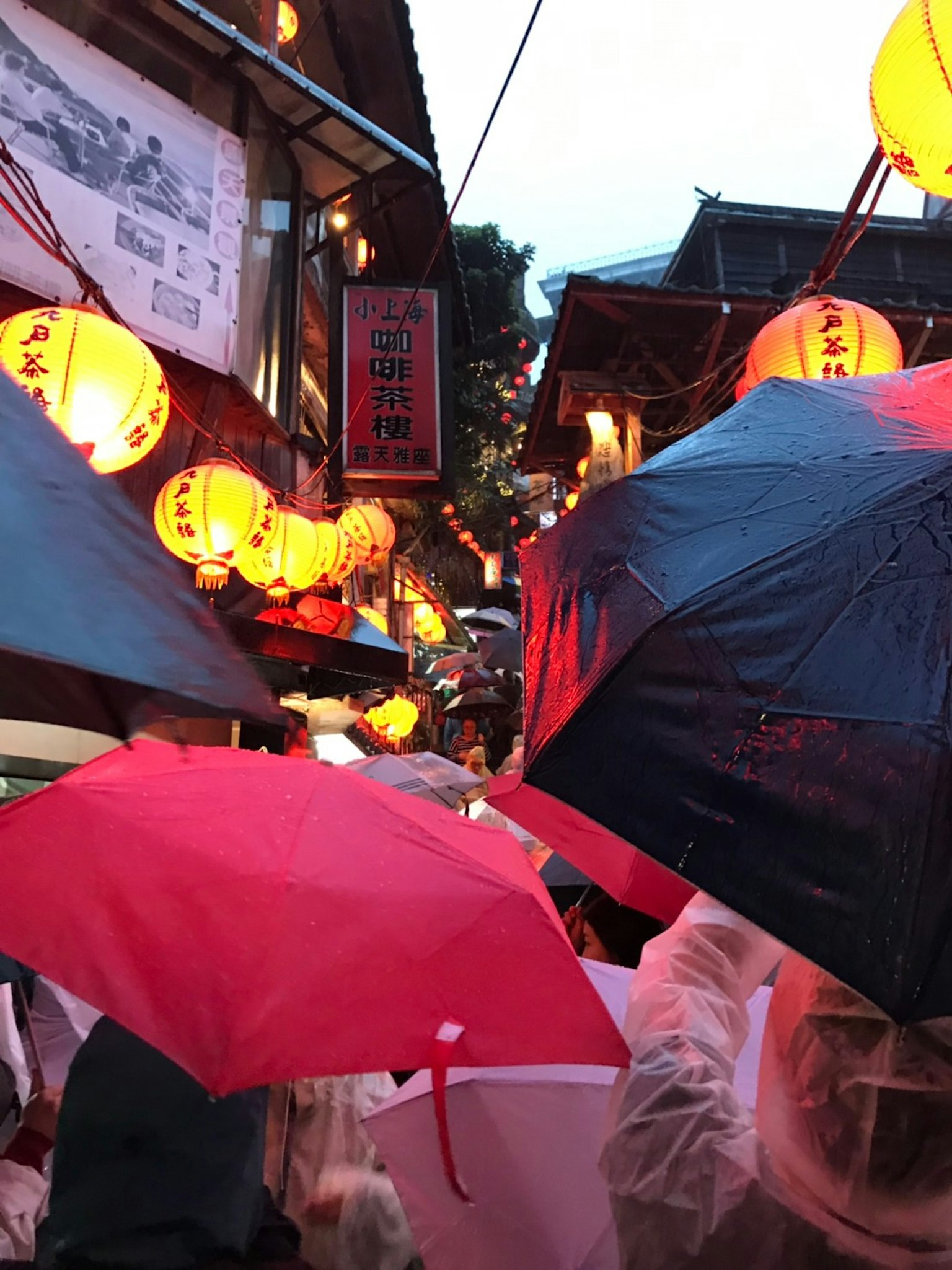 Bunte Regenschirme in einer engen Straße, die nachts von Laternen beleuchtet wird