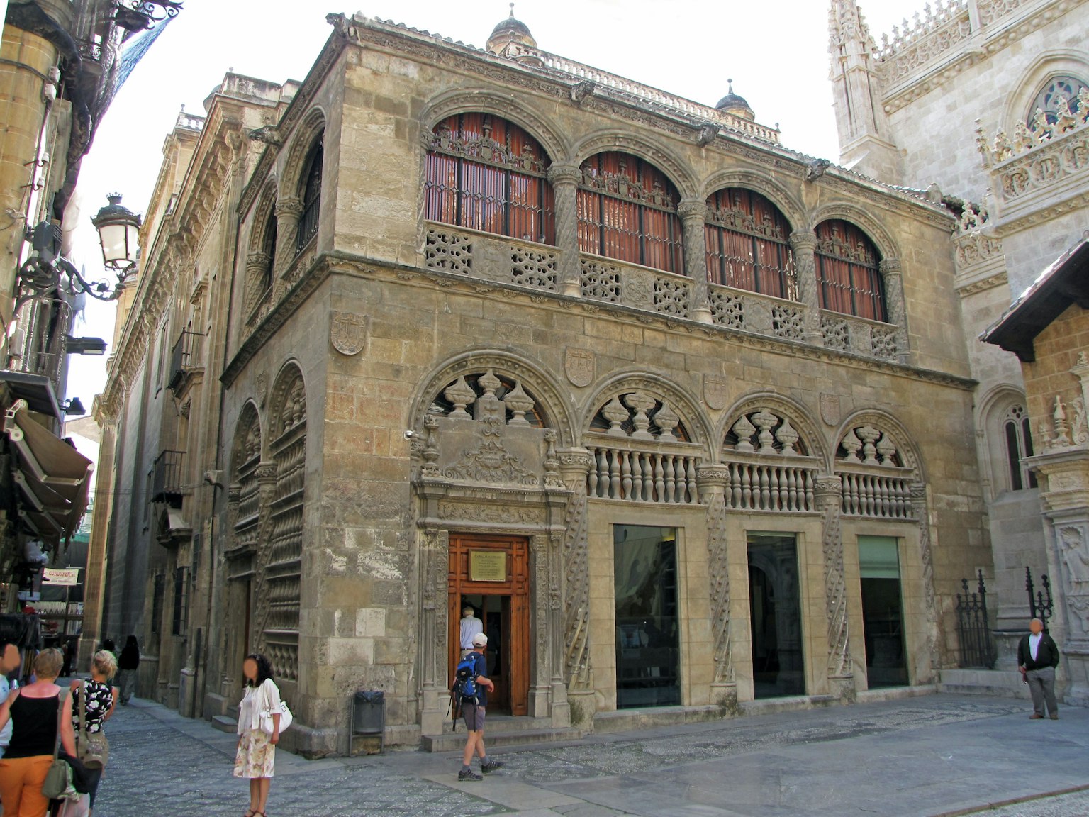 Exterior de un edificio histórico con fachada de piedra y ventanas decorativas