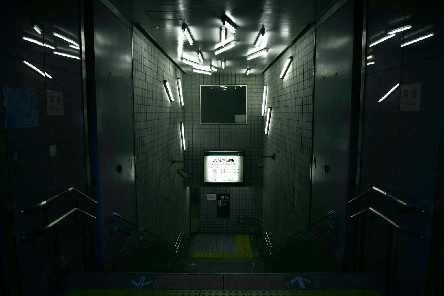 Interior elevator gelap dengan monitor putih dan lampu strip bercahaya