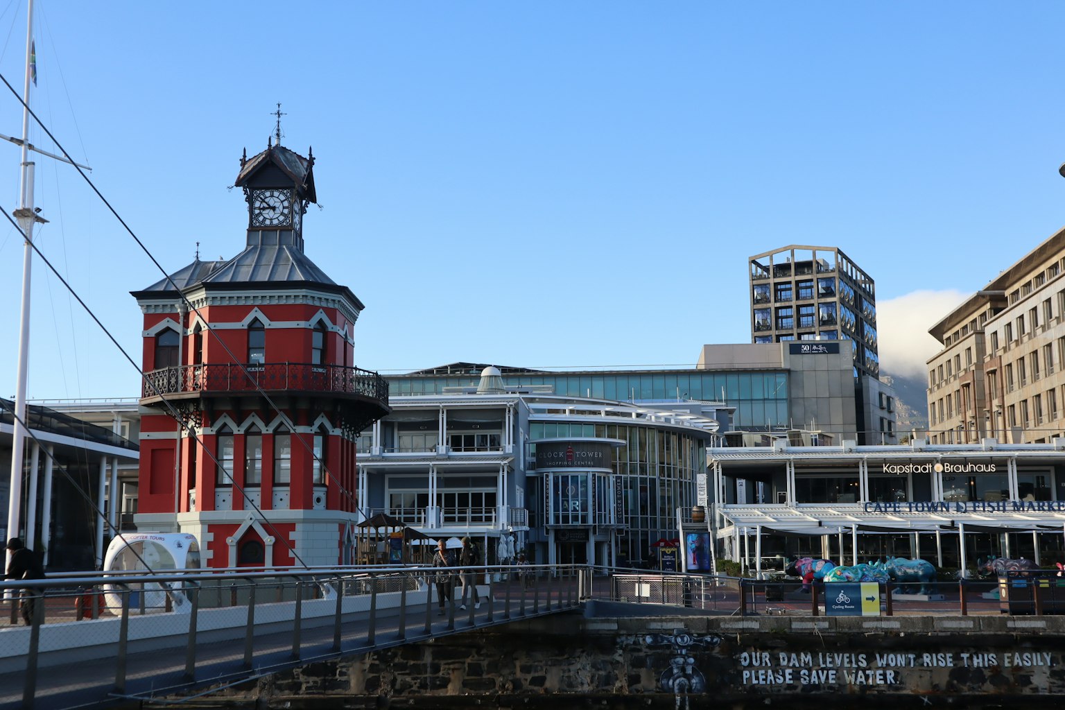 Menara jam merah di dekat pelabuhan dengan bangunan modern