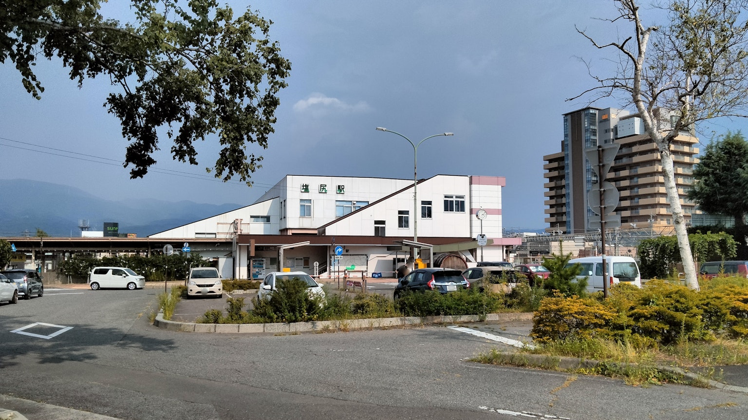 Pemandangan parkir dan bangunan dengan langit biru dan awan