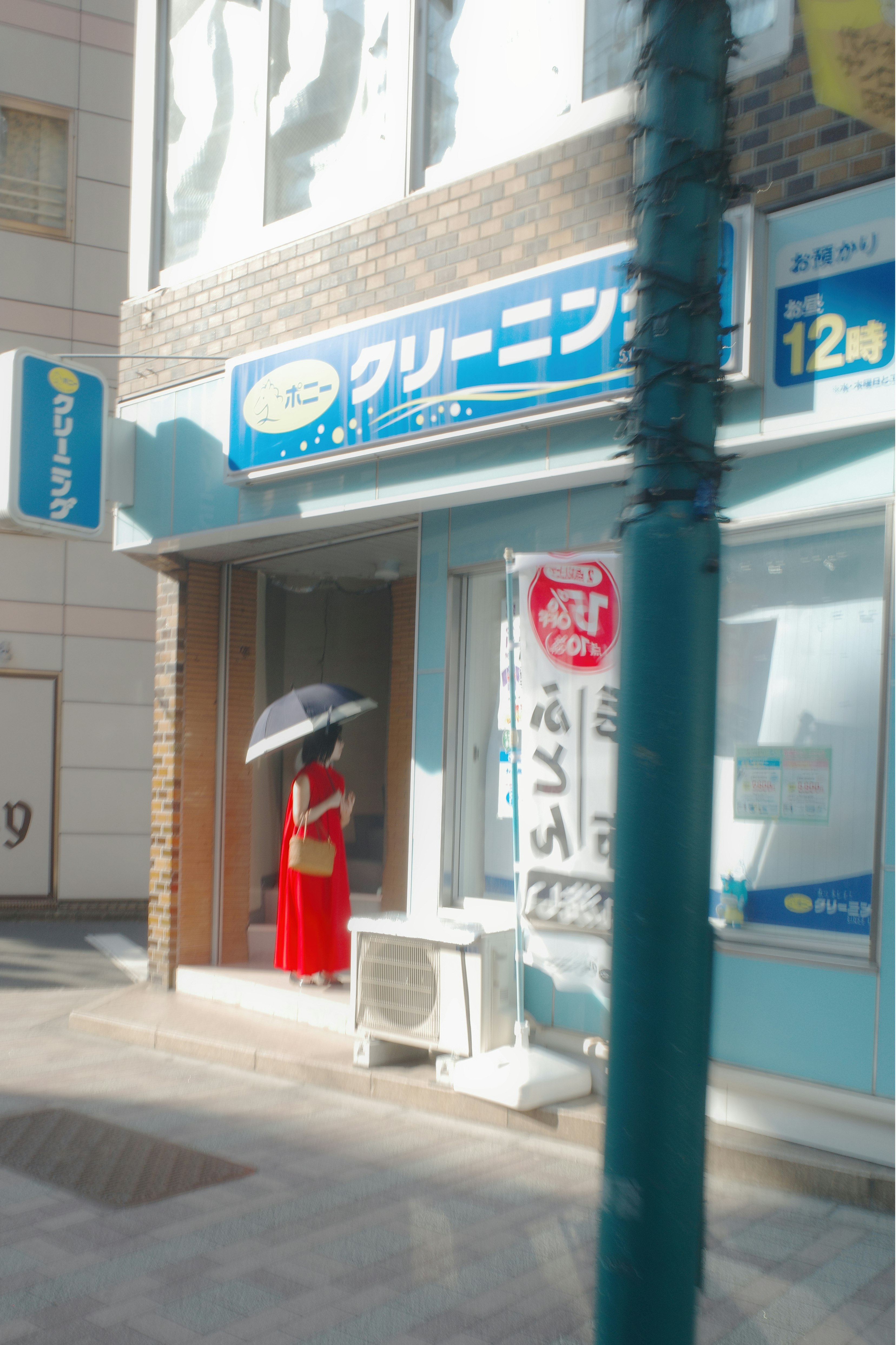 赤い制服の店員が立つ商店街の軒先