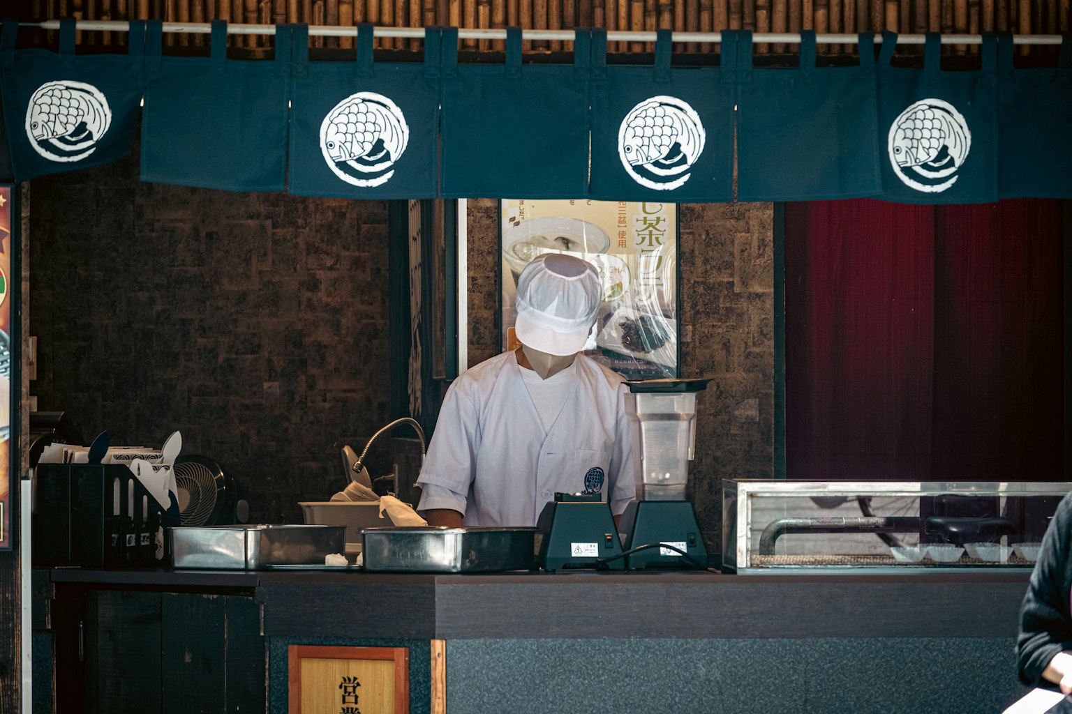 Chef che prepara il cibo al bancone indossando un grembiule bianco e un cappello