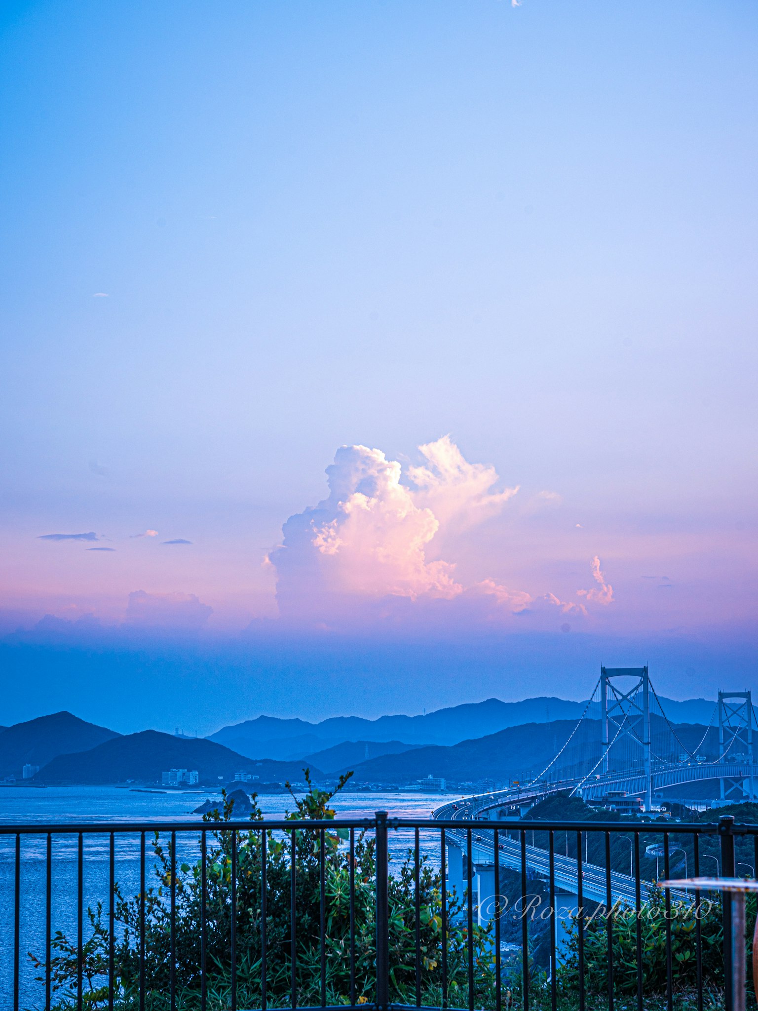 青い空と紫の雲が広がる風景 橋と山々が見える