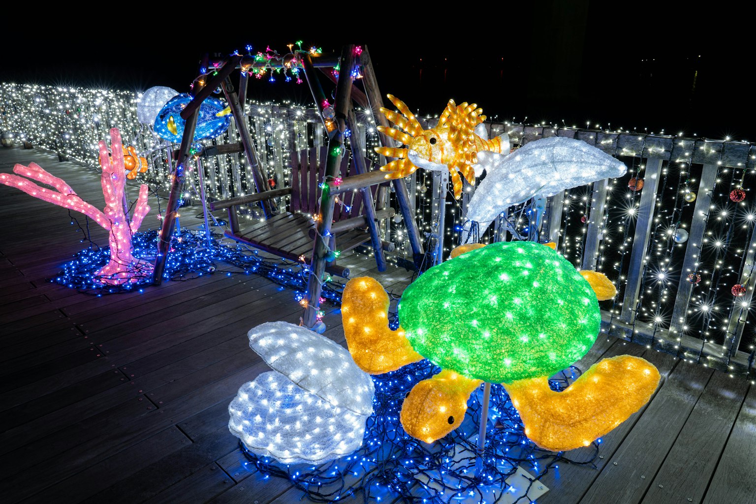 Luci colorate che decorano un'altalena e sculture di creature marine