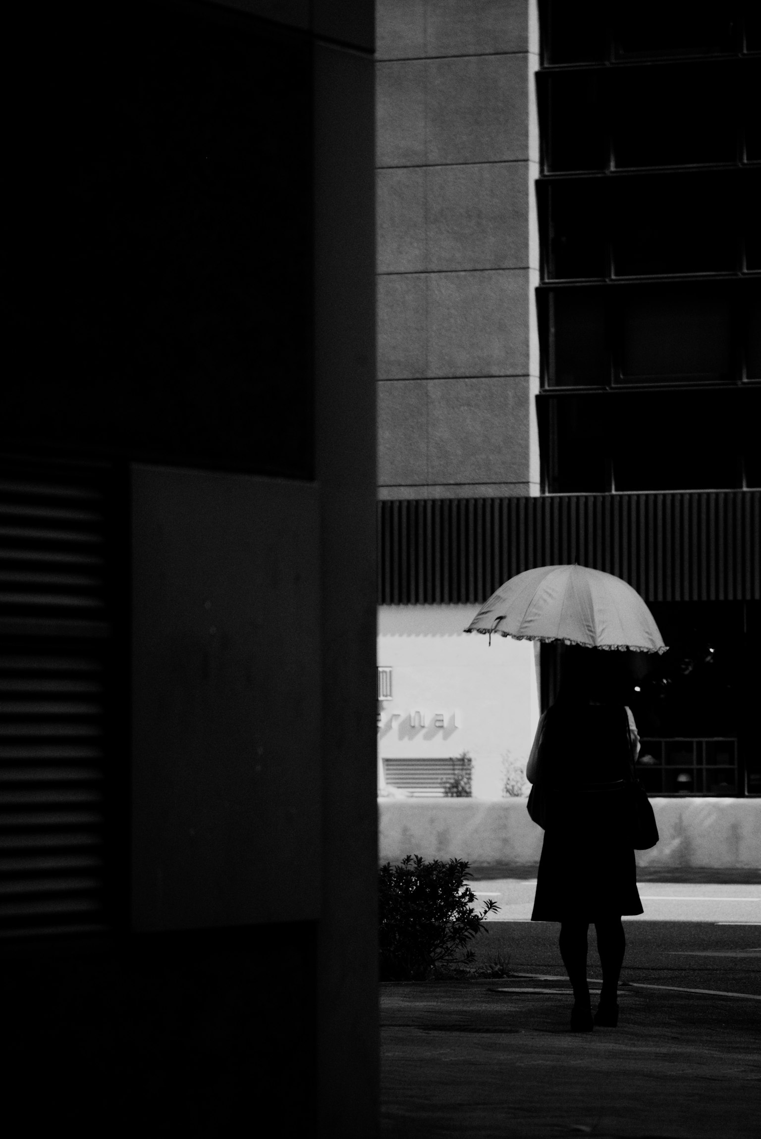 Une femme portant un parapluie marchant dans un cadre urbain monochrome