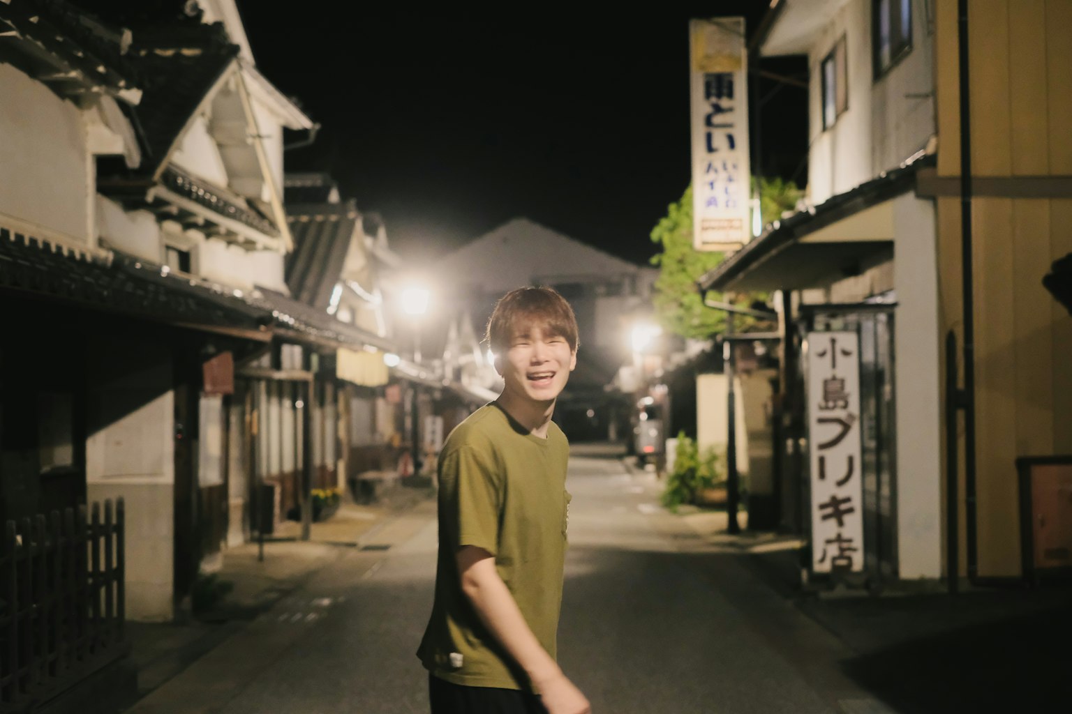 A smiling man walking in a quiet street at night