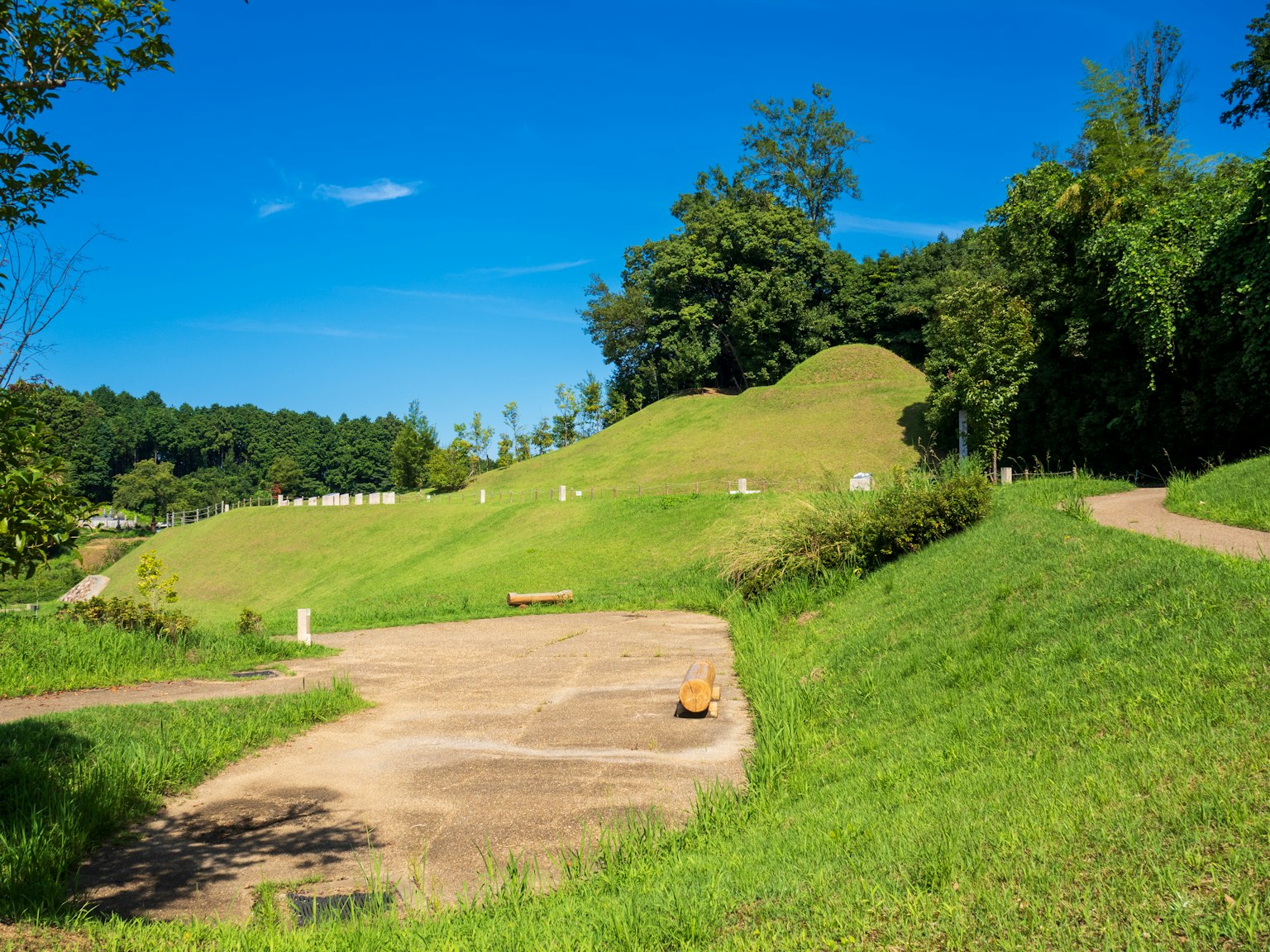 Vista panoramica di colline verdi sotto un cielo blu con sentieri e aree erbose
