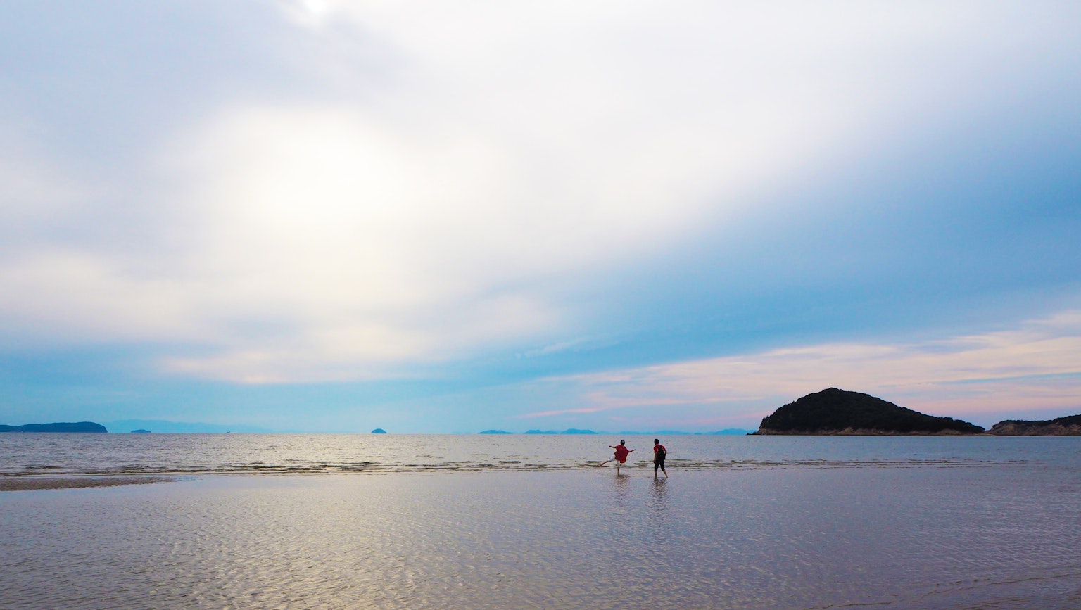 Personas caminando por una playa tranquila bajo un cielo azul