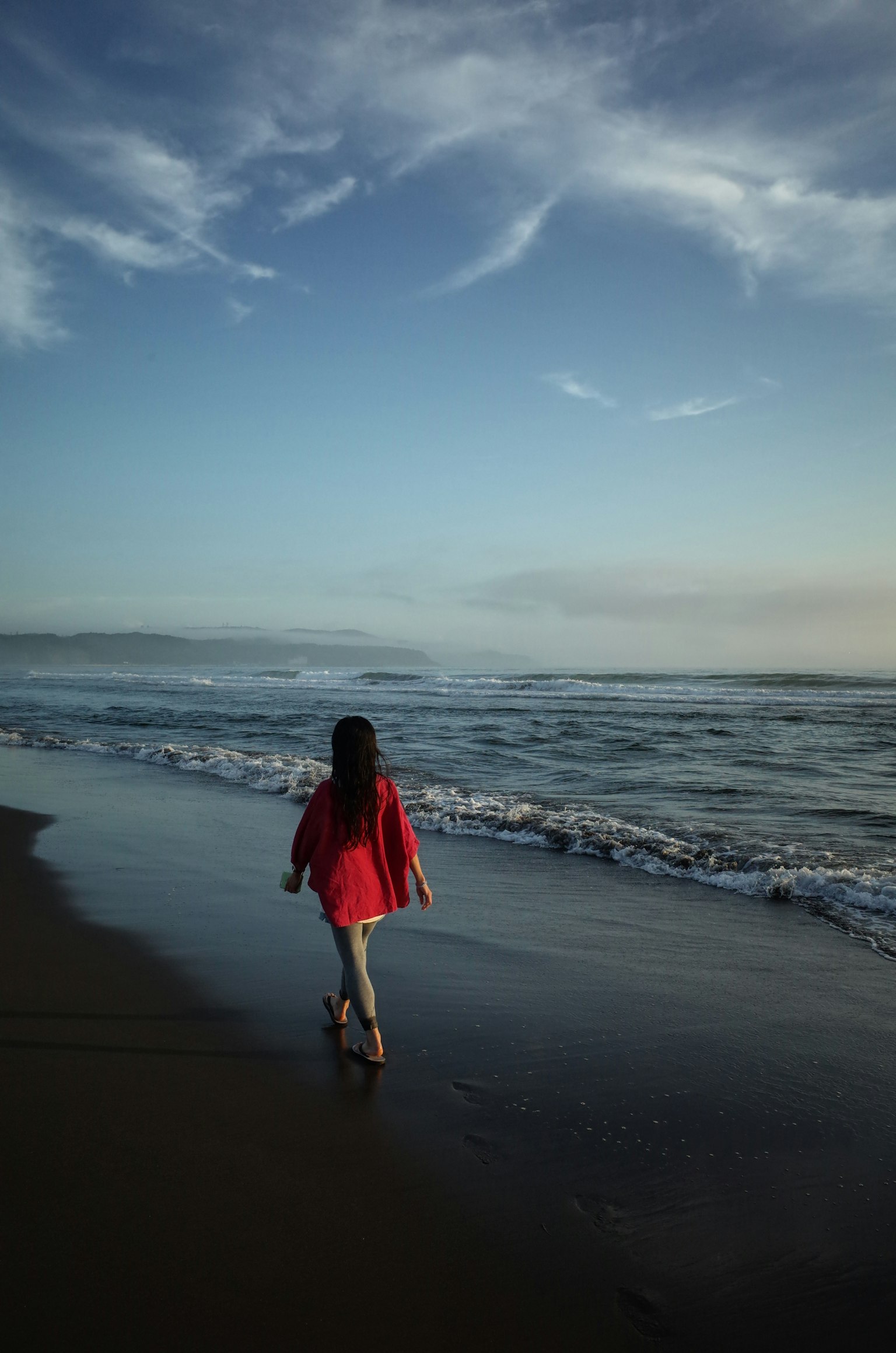 Enfant marchant sur la plage avec une veste rouge