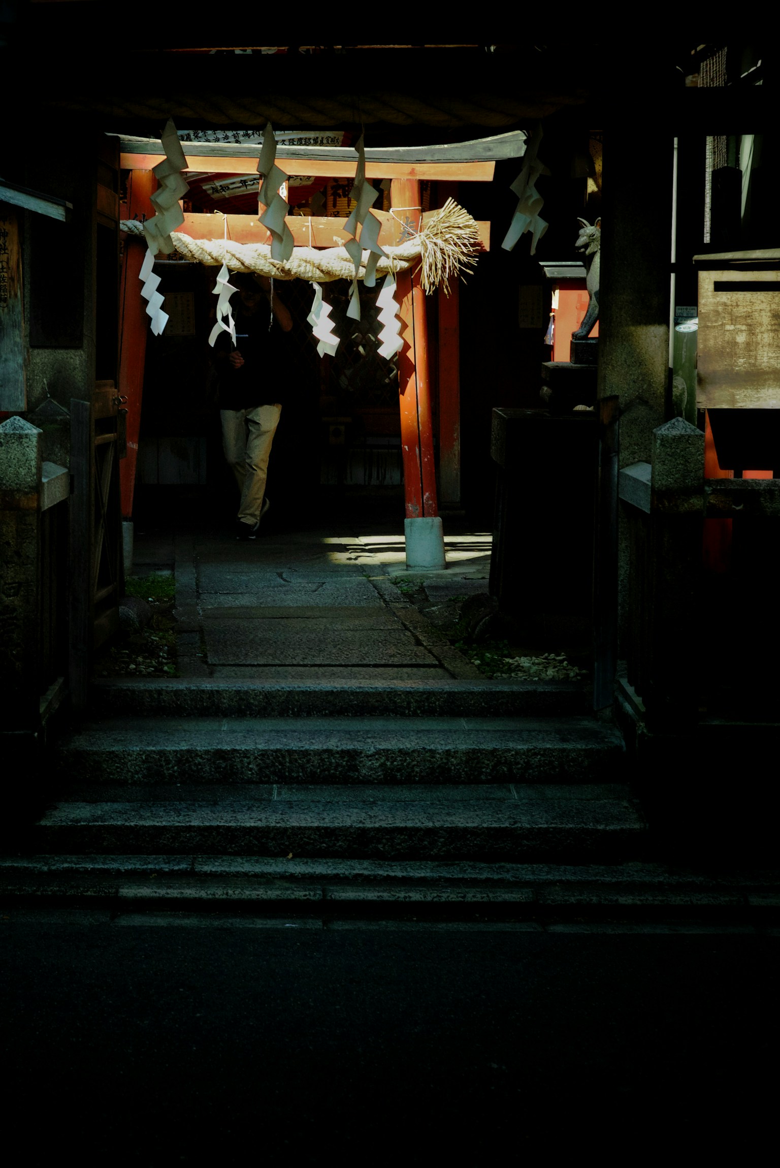 Entrance of a shrine with stone steps and shimenawa decoration