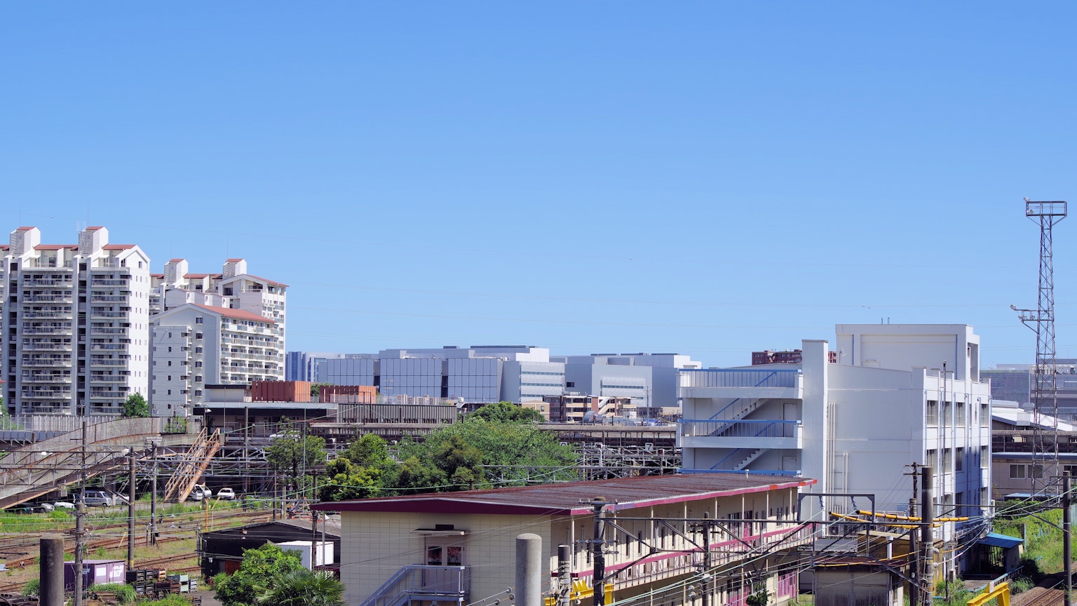 ทิวทัศน์เมืองใต้ท้องฟ้าสีฟ้าพร้อมรางรถไฟและอาคาร