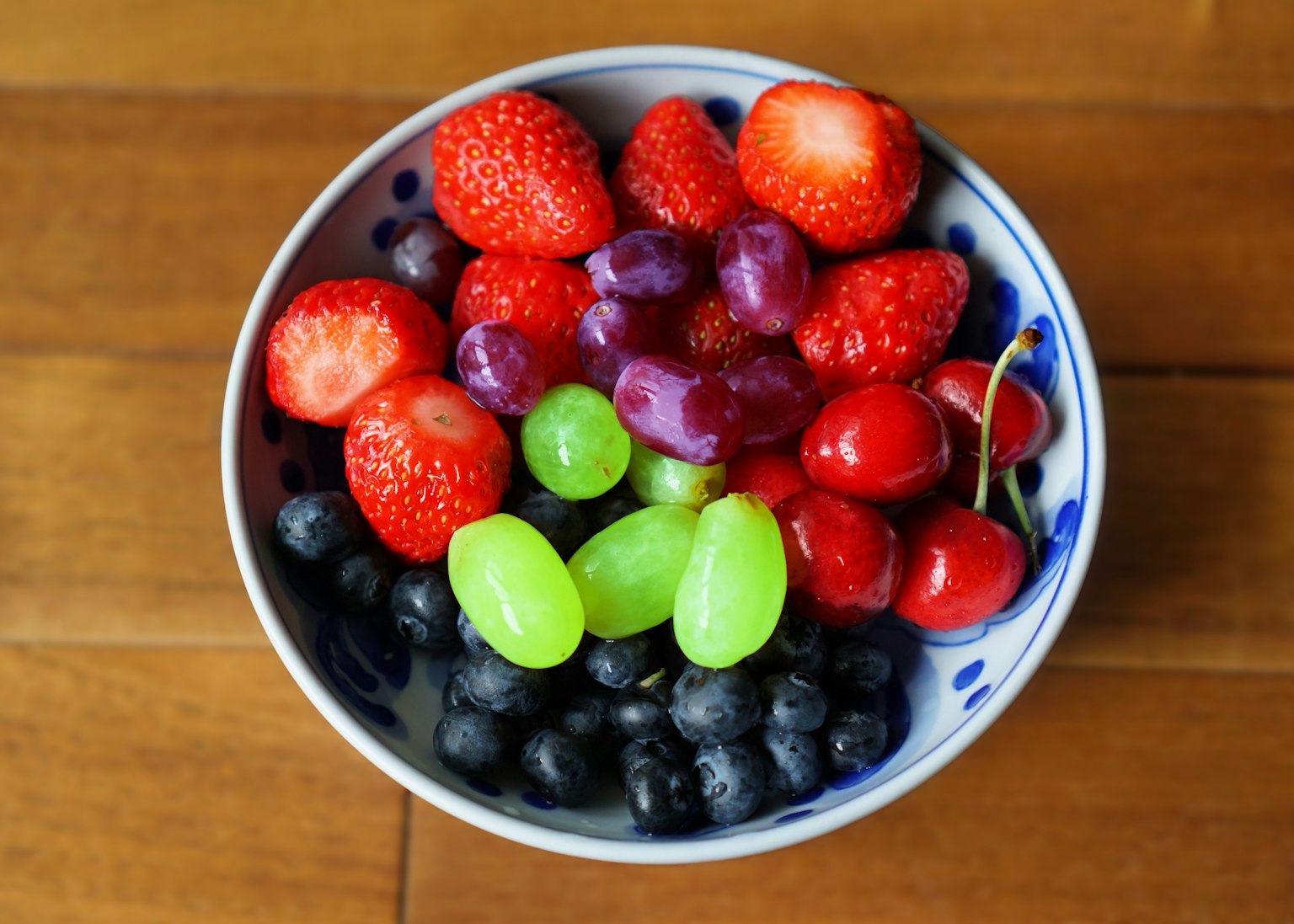 Un bol rempli d'une variété de fruits colorés comprenant des fraises, des raisins et des myrtilles