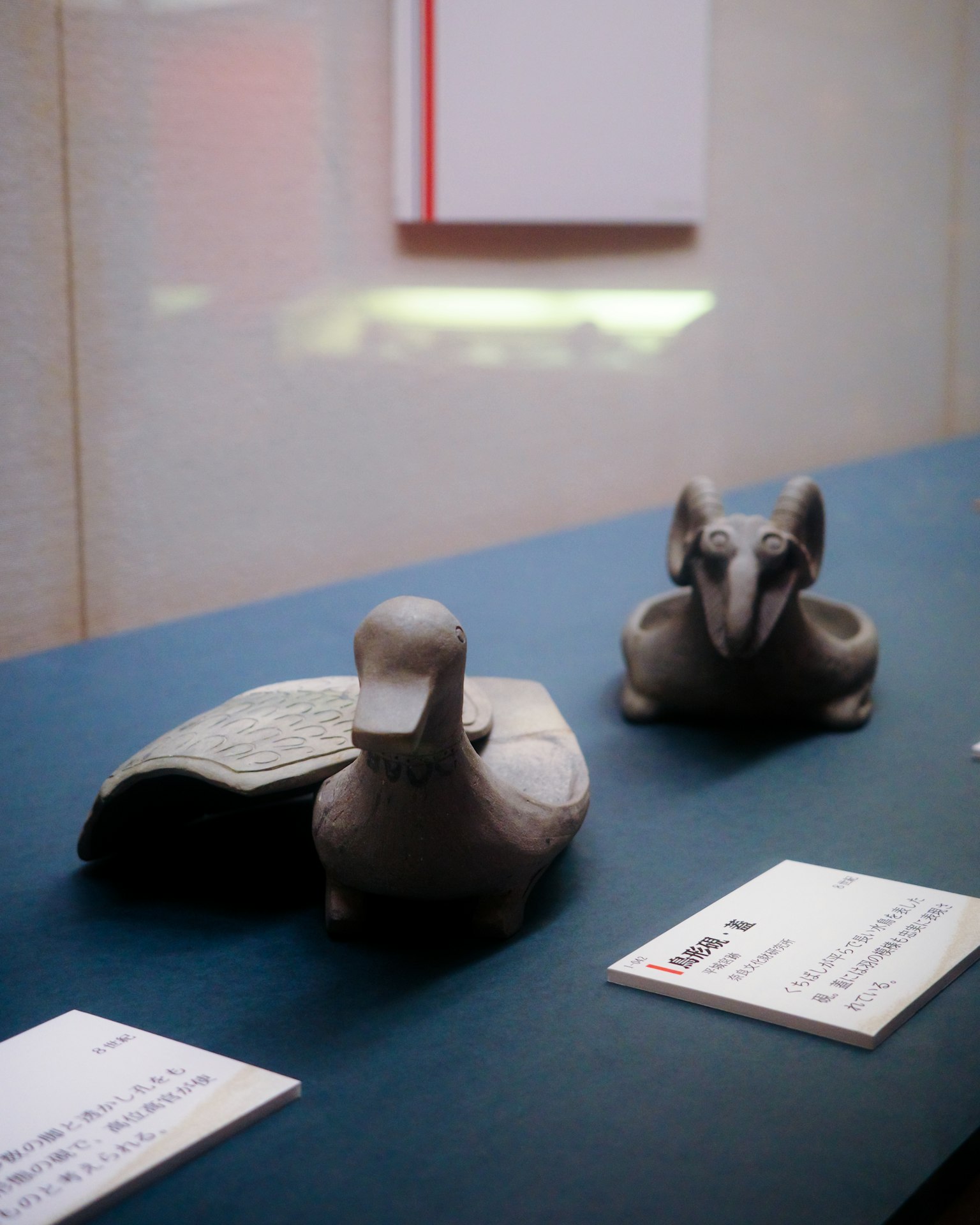 Esculturas de cerámica de pato y oveja en una mesa de exhibición