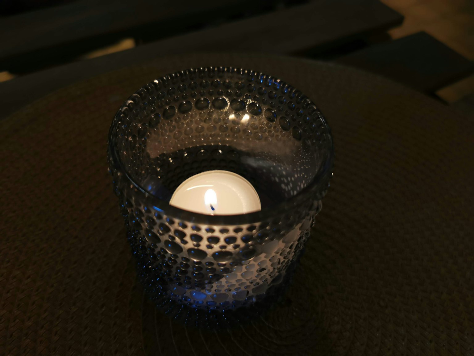 Blue candle holder with water droplets and white candle inside