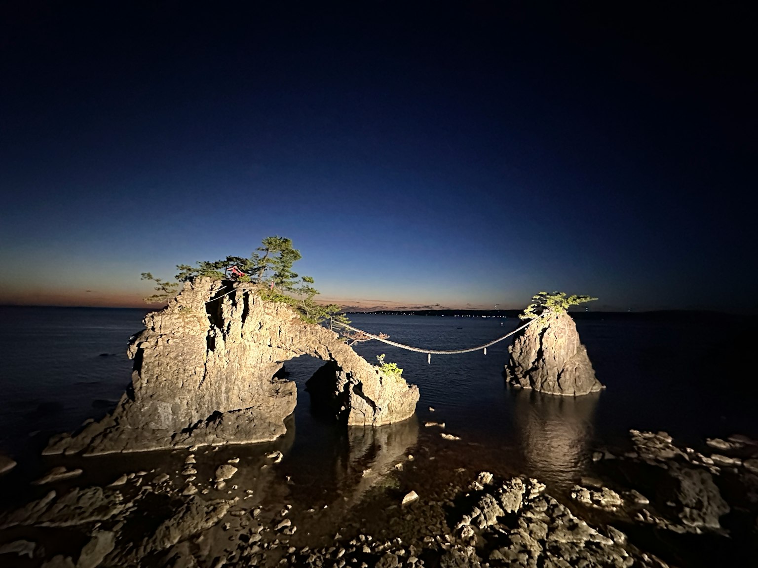 Due formazioni rocciose di notte collegate da un ponte sull'acqua