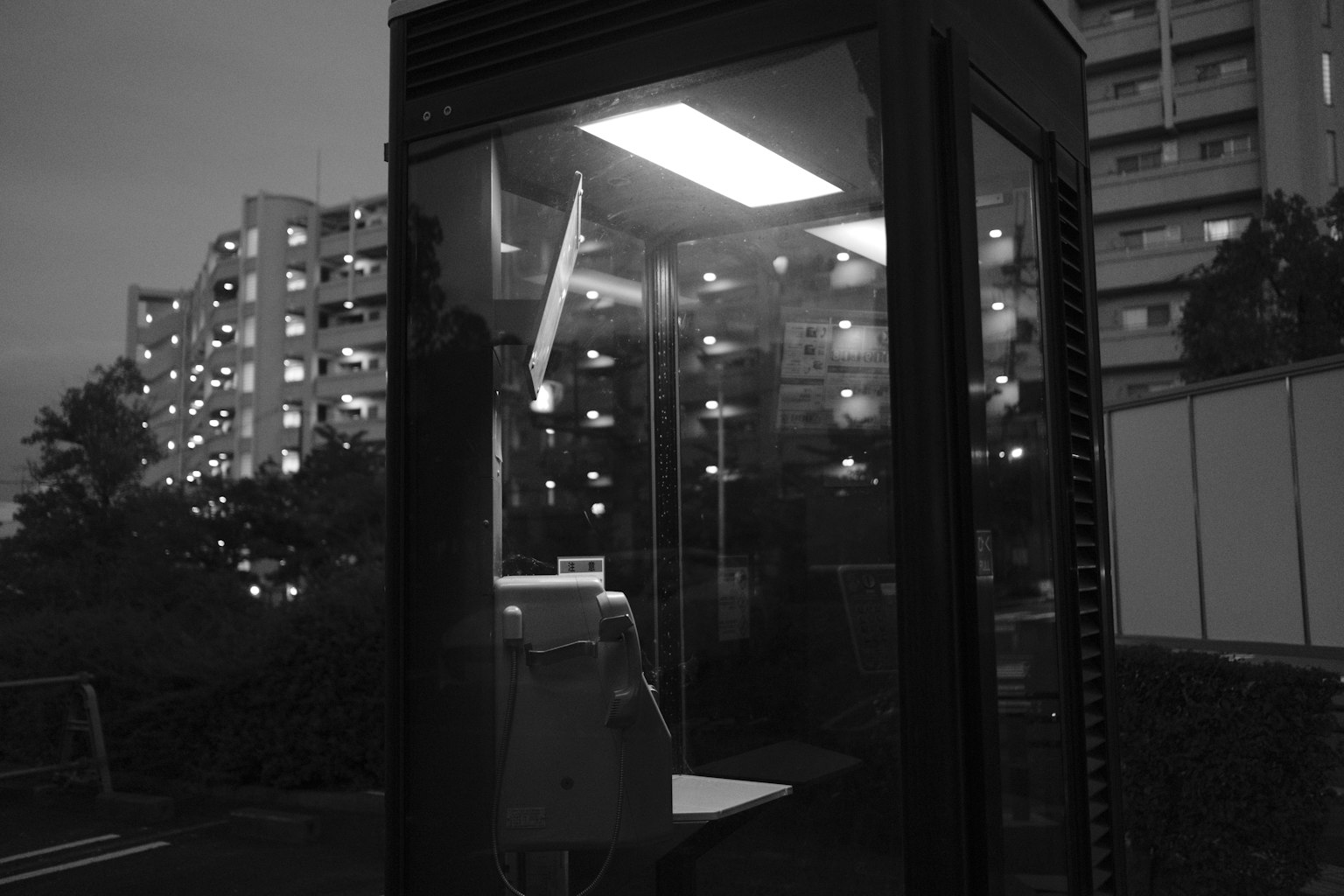 Cabine téléphonique éclairée la nuit avec des bâtiments environnants