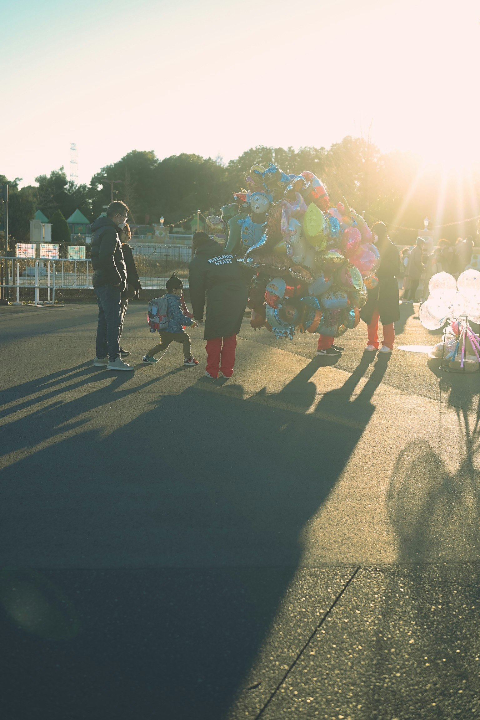 Eine lebhafte Szene von Ballonverkäufern und Kindern mit dem Sonnenuntergang im Hintergrund
