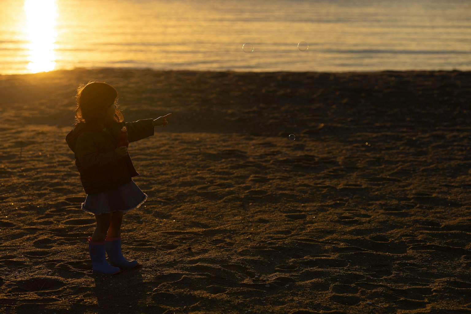 Silhouette d'un enfant jouant sur la plage avec le coucher de soleil en arrière-plan