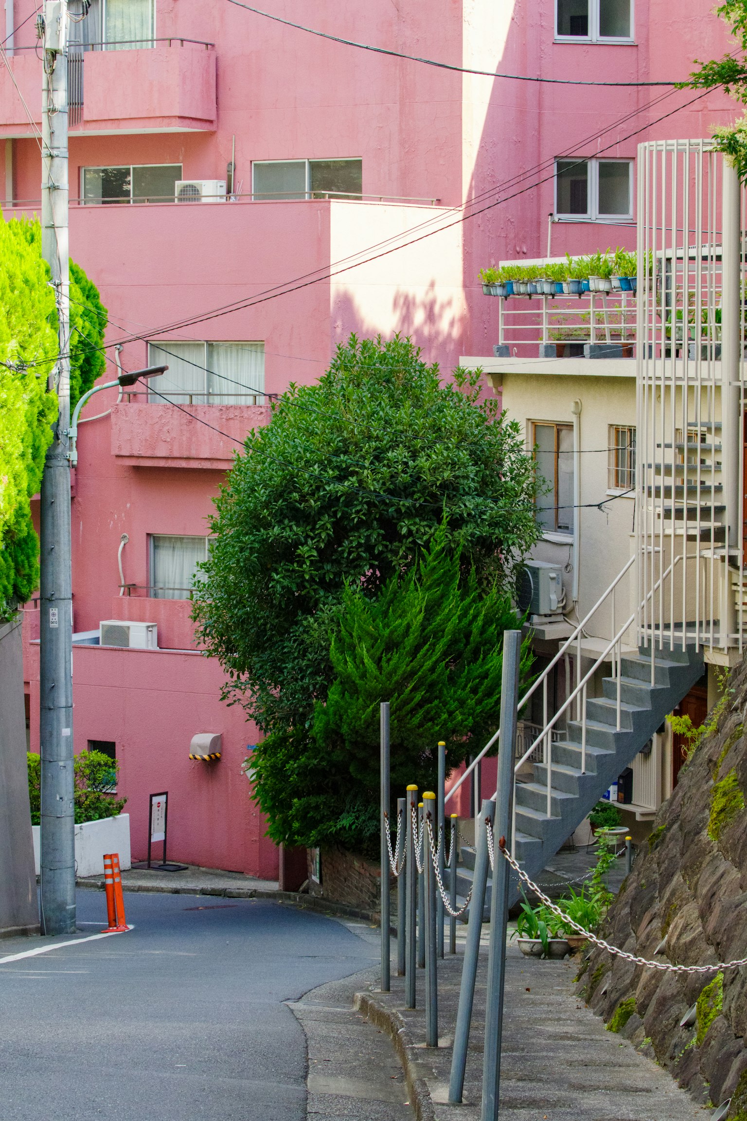 Scène de rue étroite avec des bâtiments roses et des arbres verts