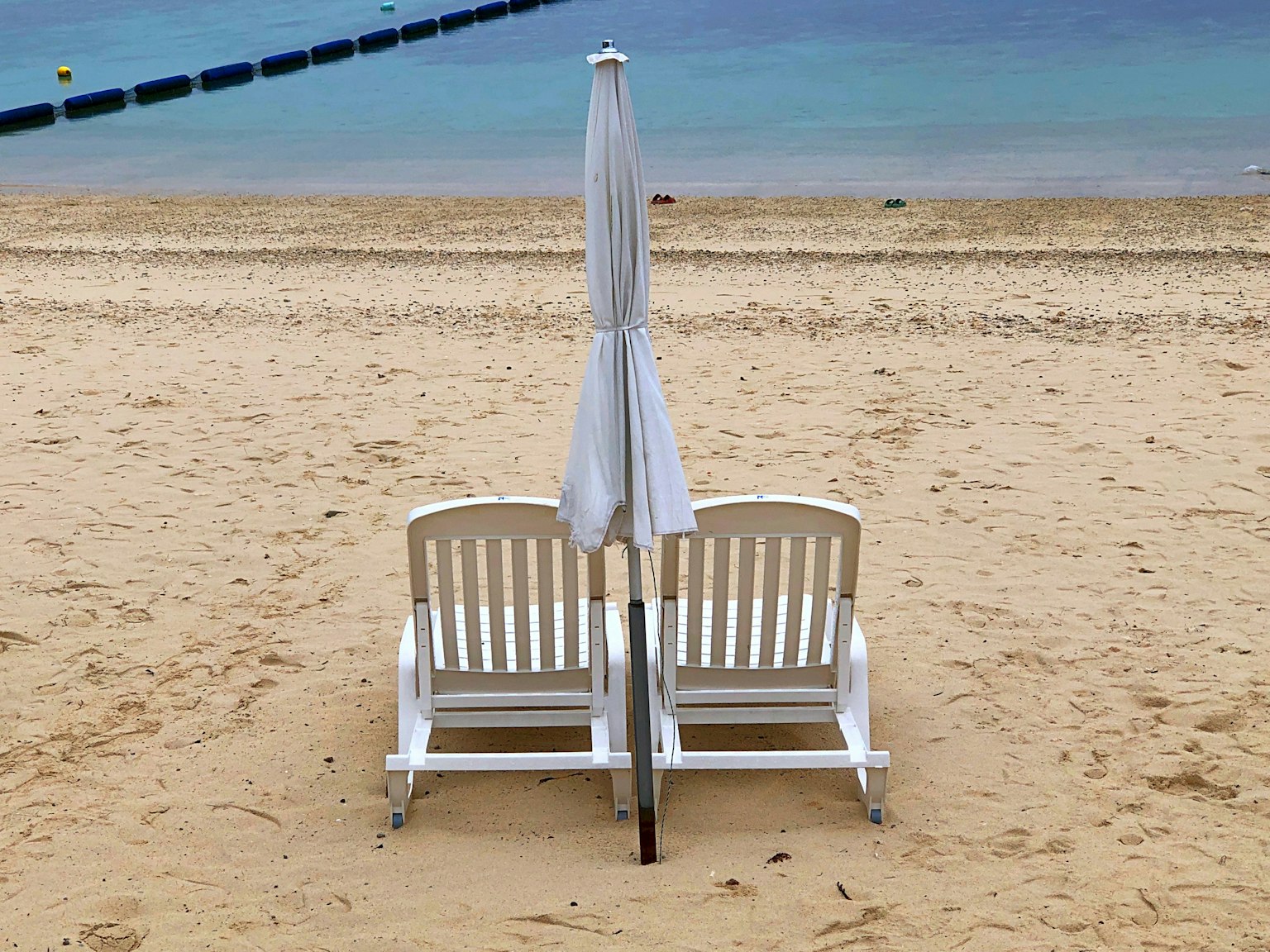 Due sdraio bianche con un ombrellone sulla spiaggia sabbiosa