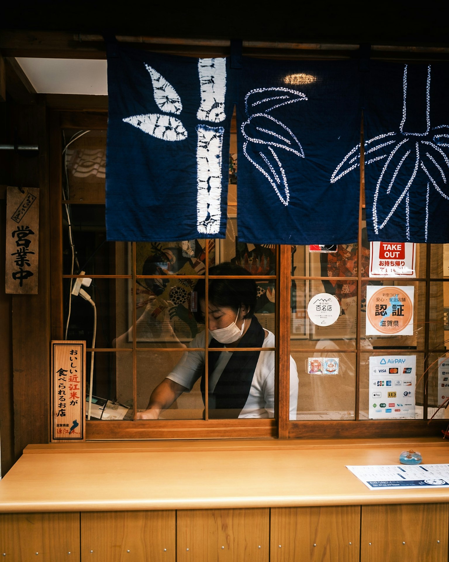 A traditional Japanese shop with a wooden counter and a staff member visible through the shoji window