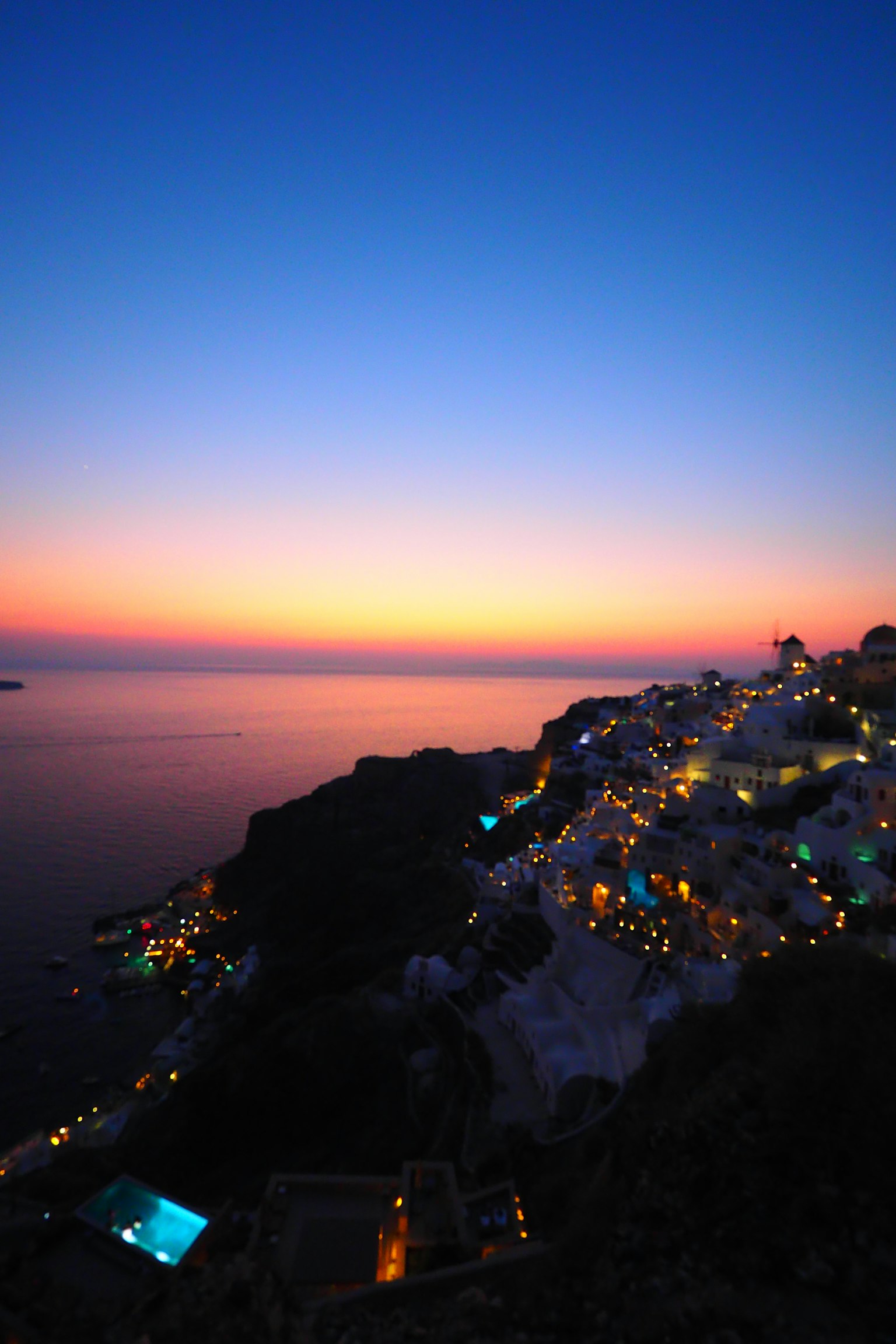 Belle vue du coucher de soleil à Santorin Océan réfléchissant un ciel en dégradé orange et bleu Bâtiments blancs illuminés