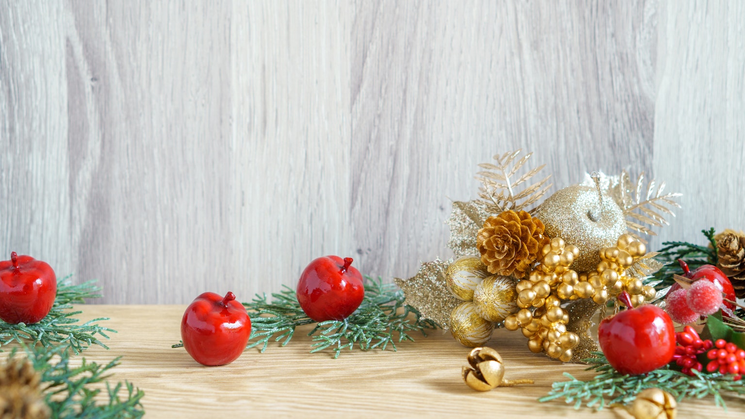 Manzanas rojas y decoraciones navideñas sobre una mesa de madera
