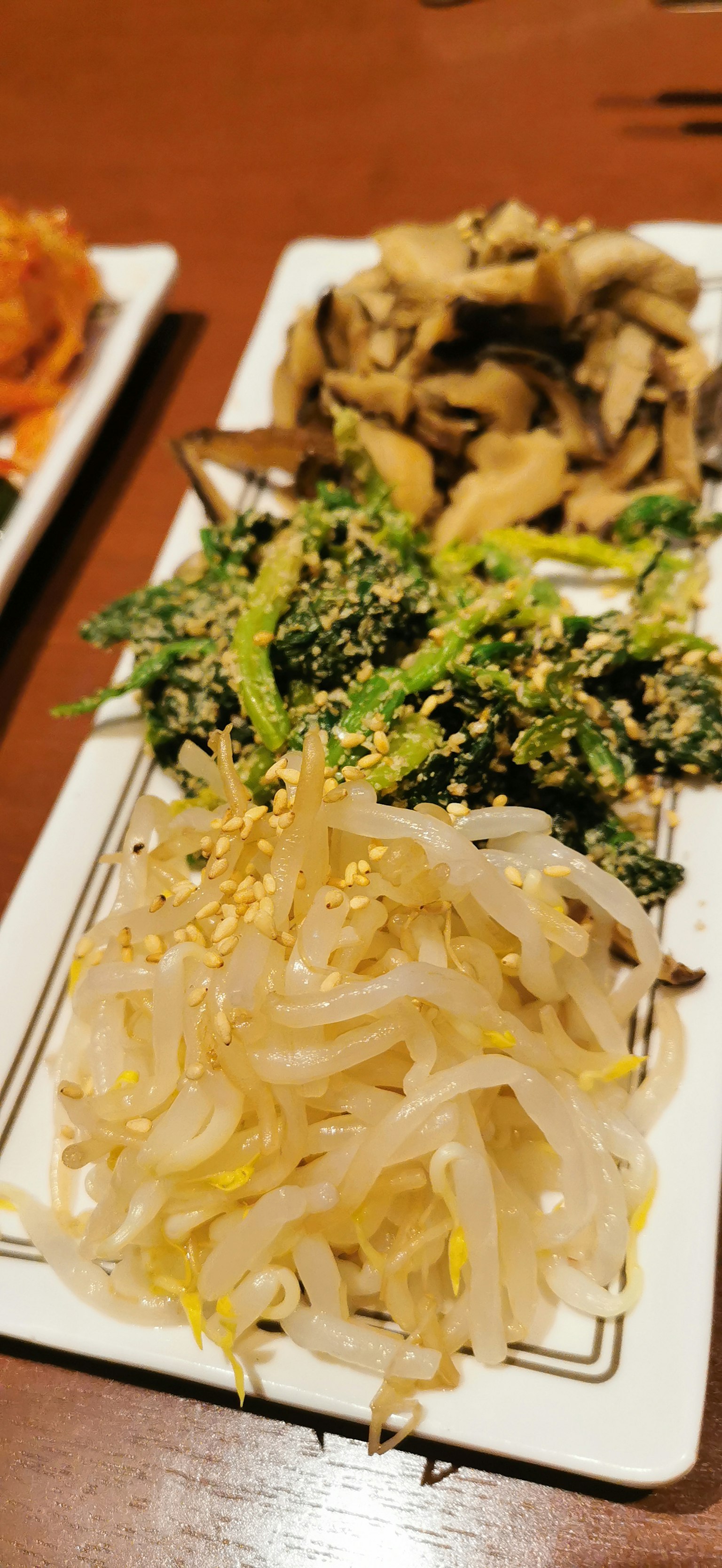一盘韩国小菜，包括美丽摆放的豆芽、绿叶菜和蘑菇