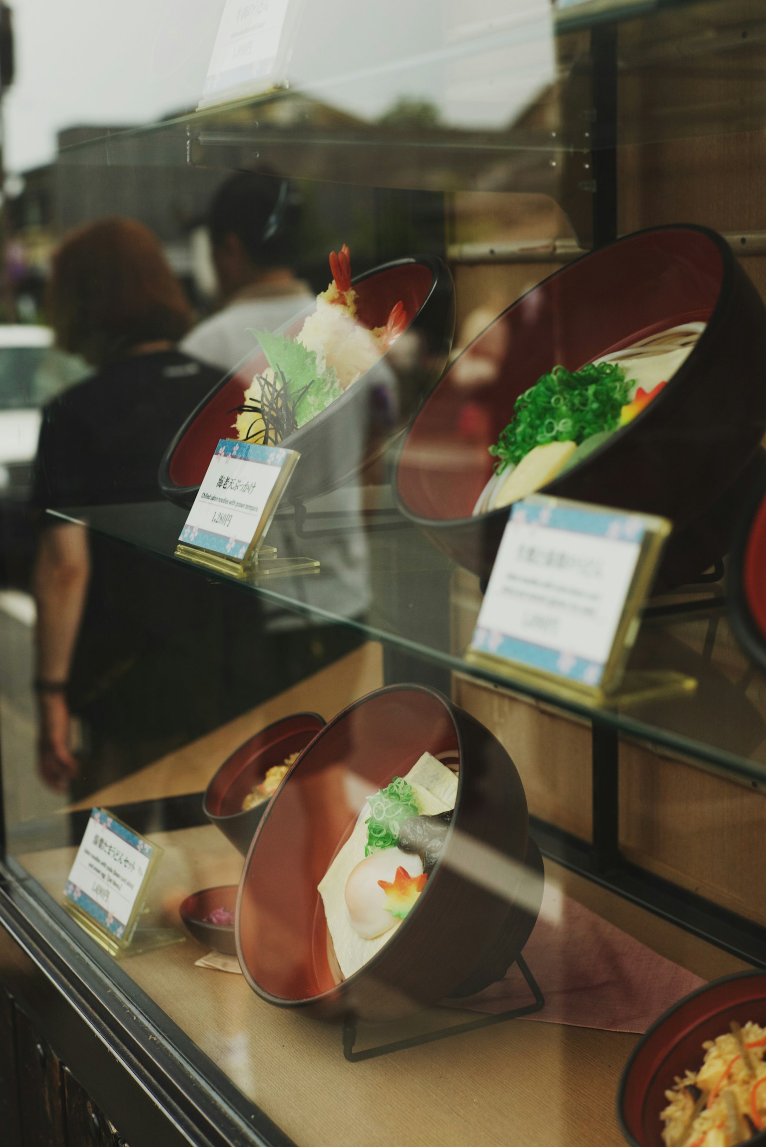 Vitrine de plats japonais avec des échantillons colorés et des légumes verts