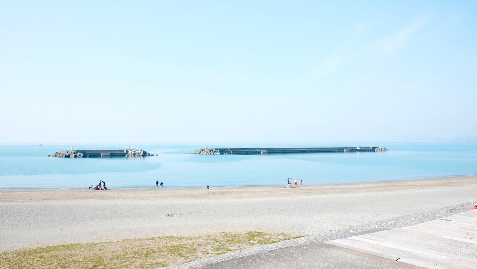 Un paesaggio di spiaggia sereno con mare calmo e moli lontani sotto un cielo azzurro