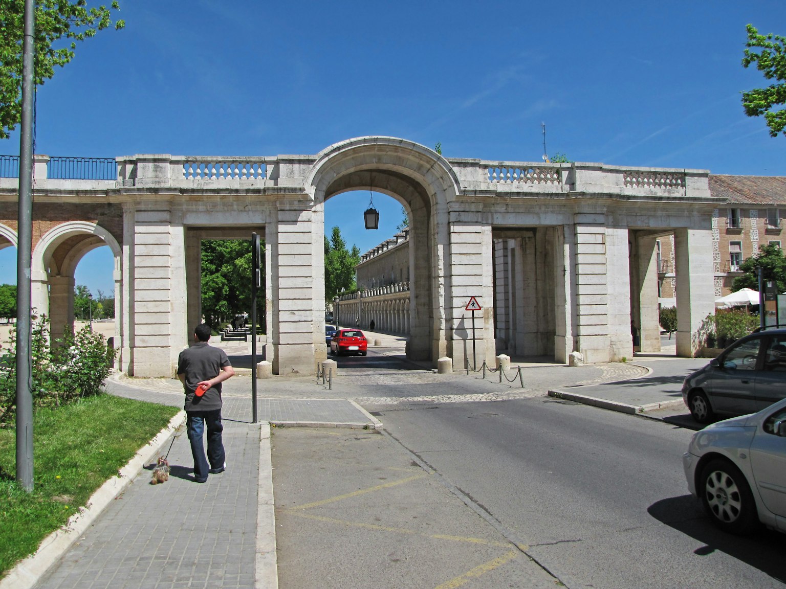 Un grande arco sotto un cielo blu con una persona che cammina per strada