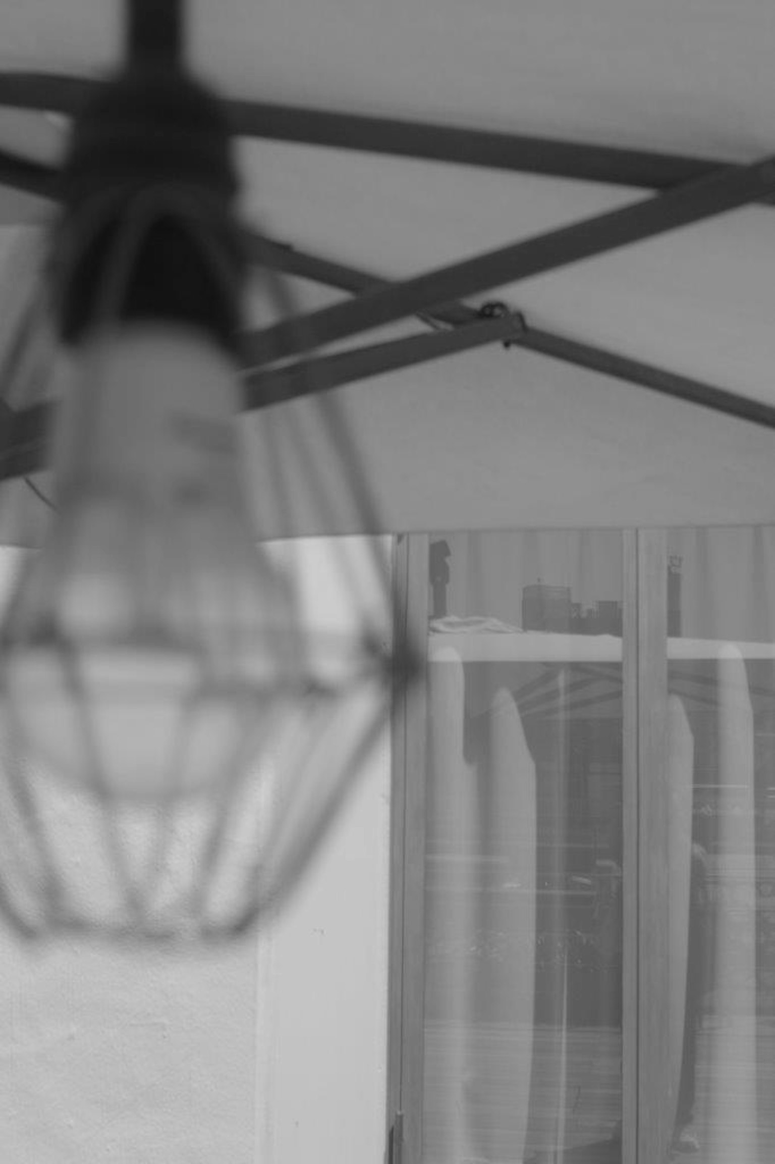 A wire-caged light bulb hanging in a black and white setting with curtains in the background