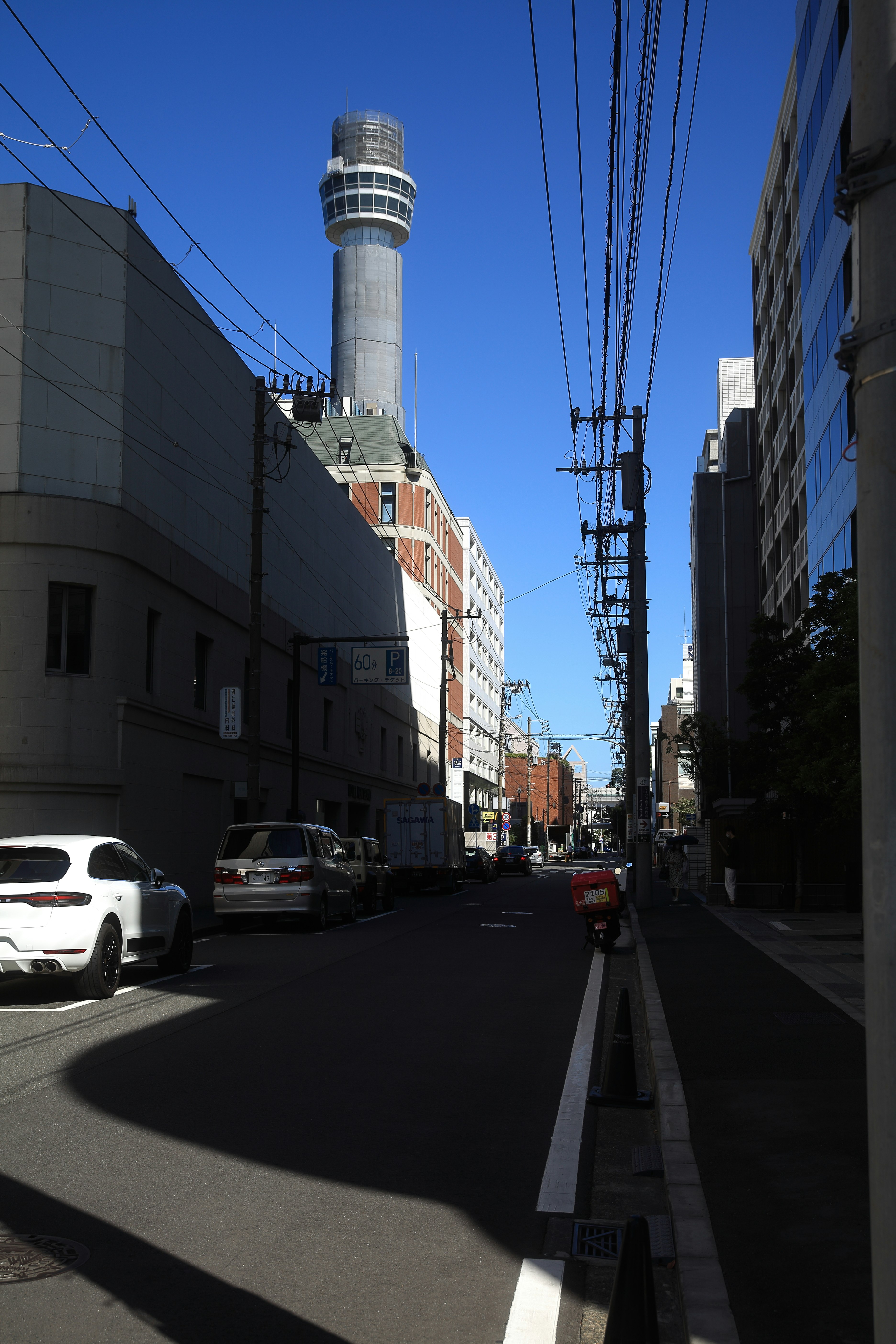 青空の下、ビル街の直線道路と電線のある風景