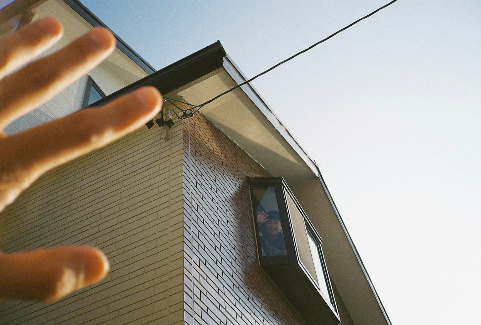 Una mano che si allunga verso una casa con cielo blu chiaro