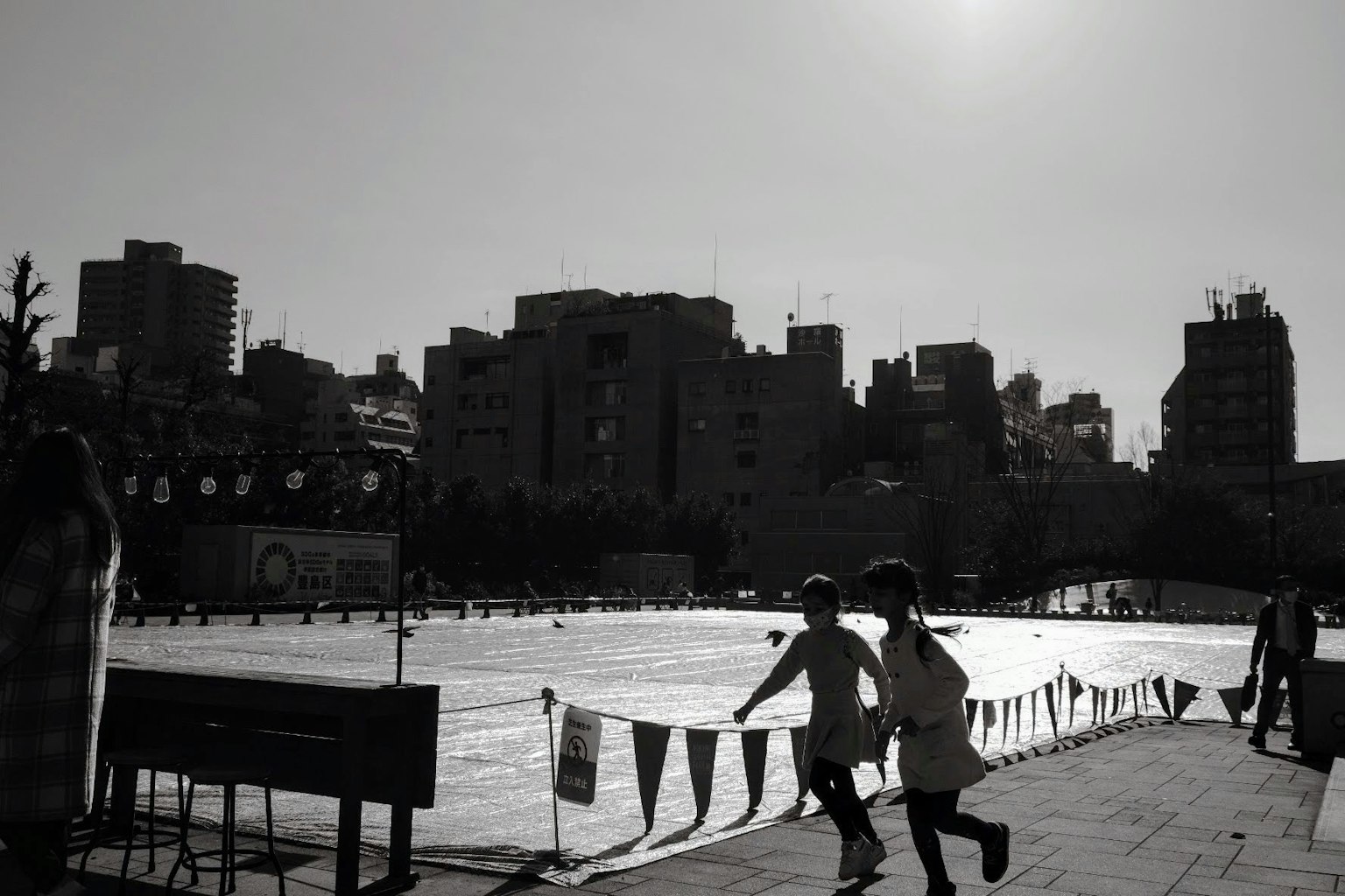 Children running in a black and white urban park scene