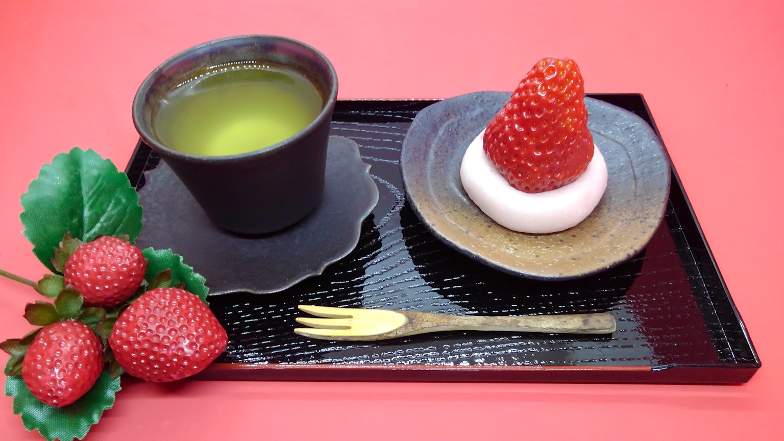 Khay với trà matcha và món tráng miệng dâu tây trên đĩa đen