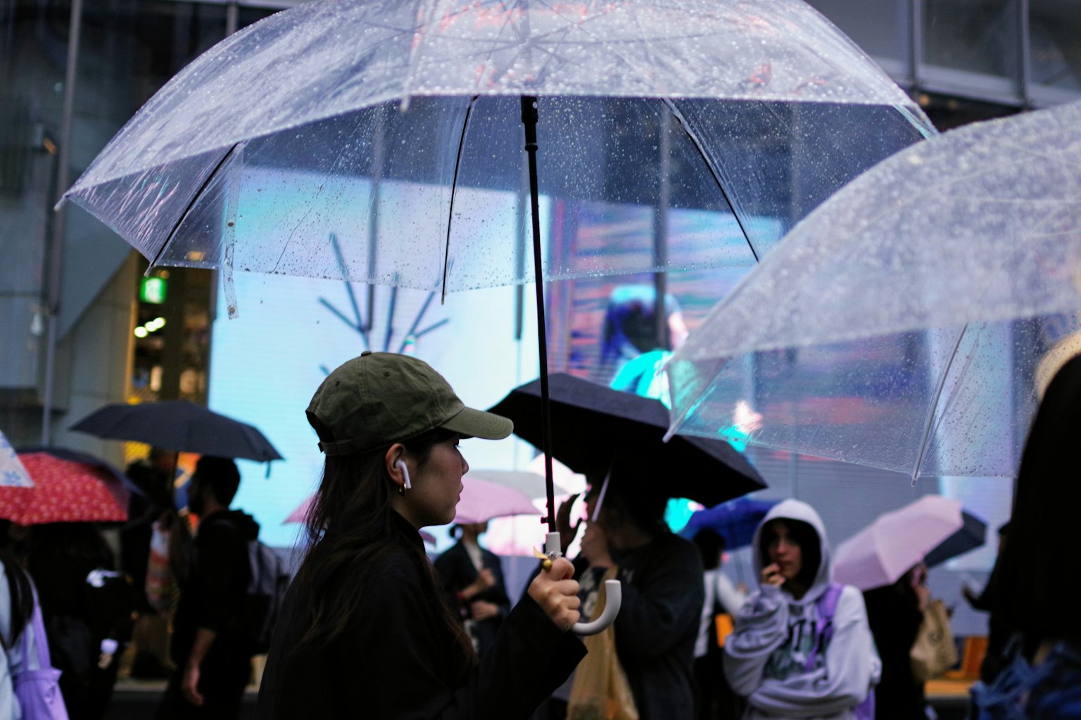 Crowd of people holding umbrellas in the rain bright advertisement in the dim background