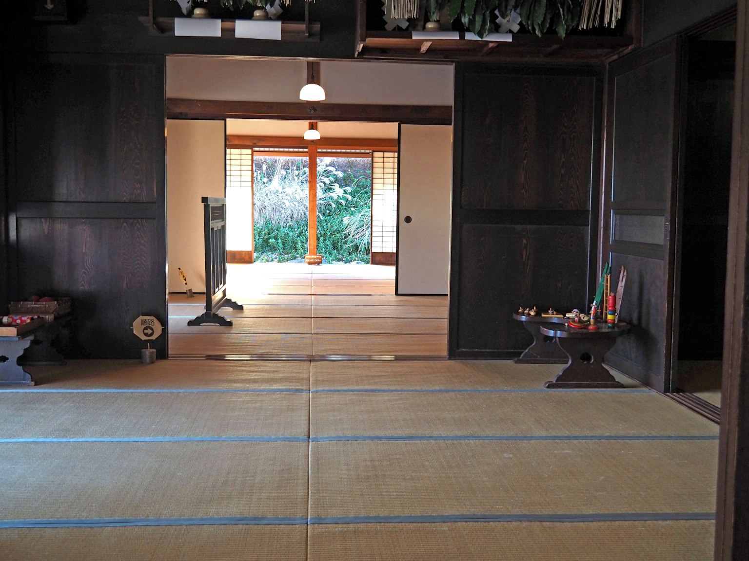 Pemandangan interior ruangan Jepang tradisional dengan lantai tatami dan dinding kayu menghadap taman