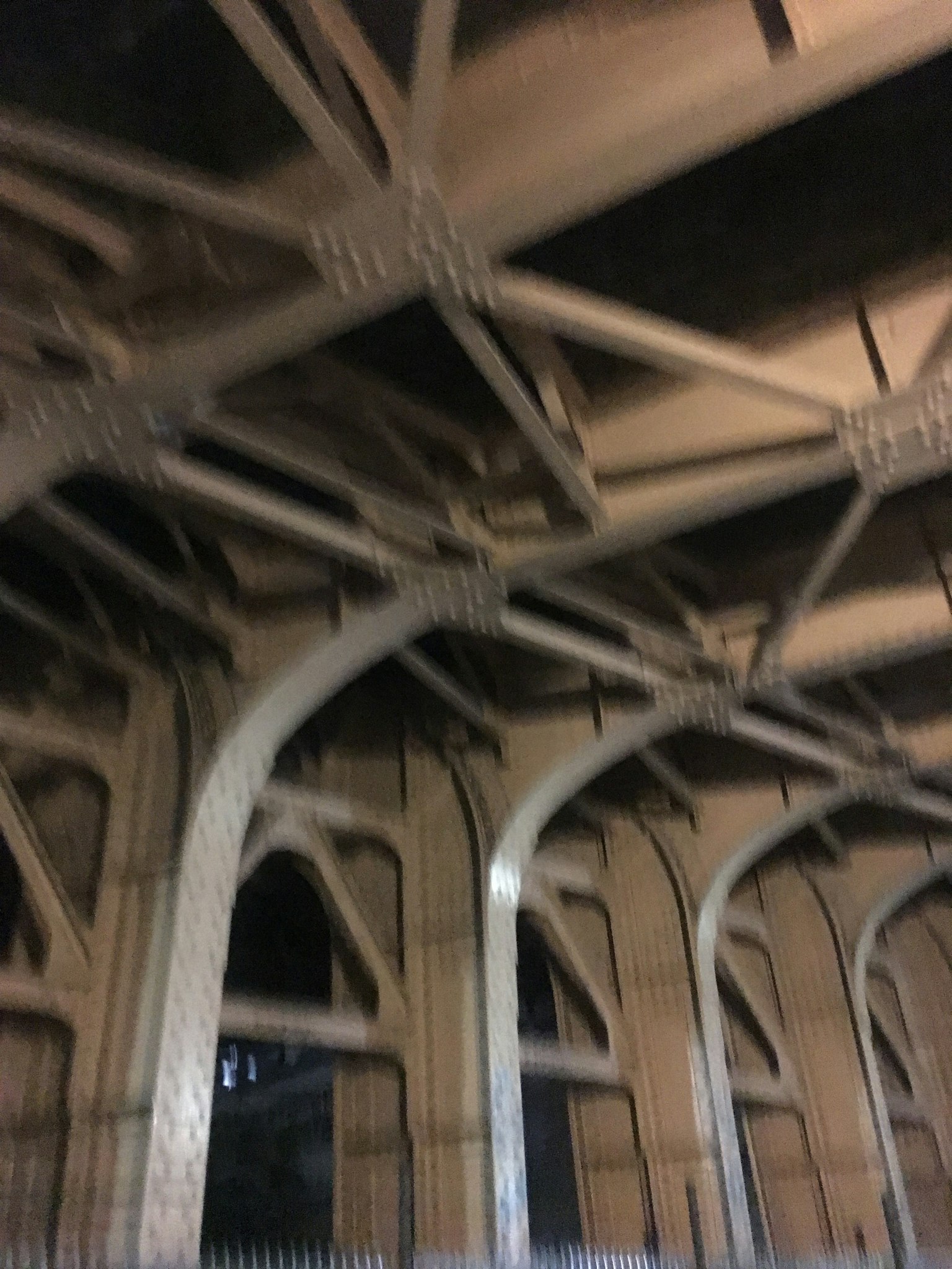 Photo of the underside of a steel bridge showing intricate arches and beams