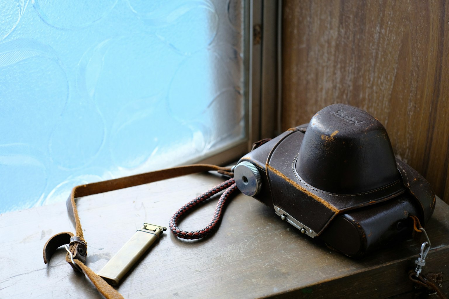 Old camera and strap placed on a windowsill