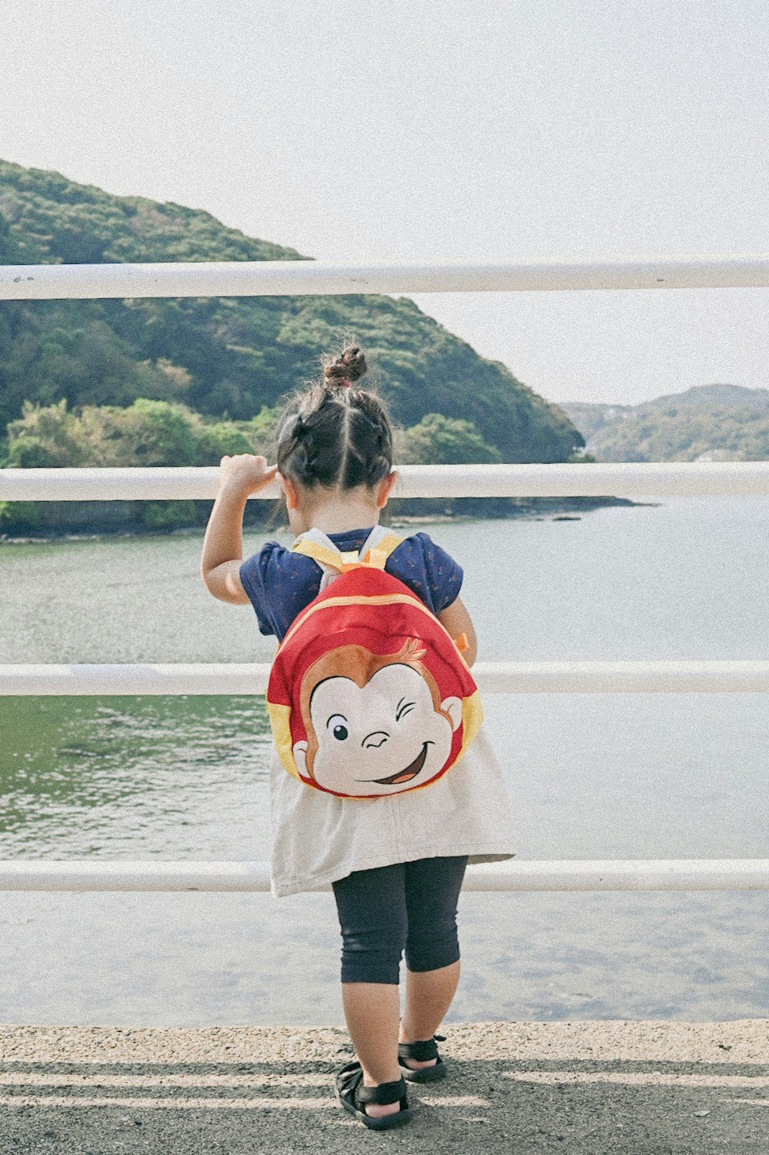 Child with a character backpack looking at the sea