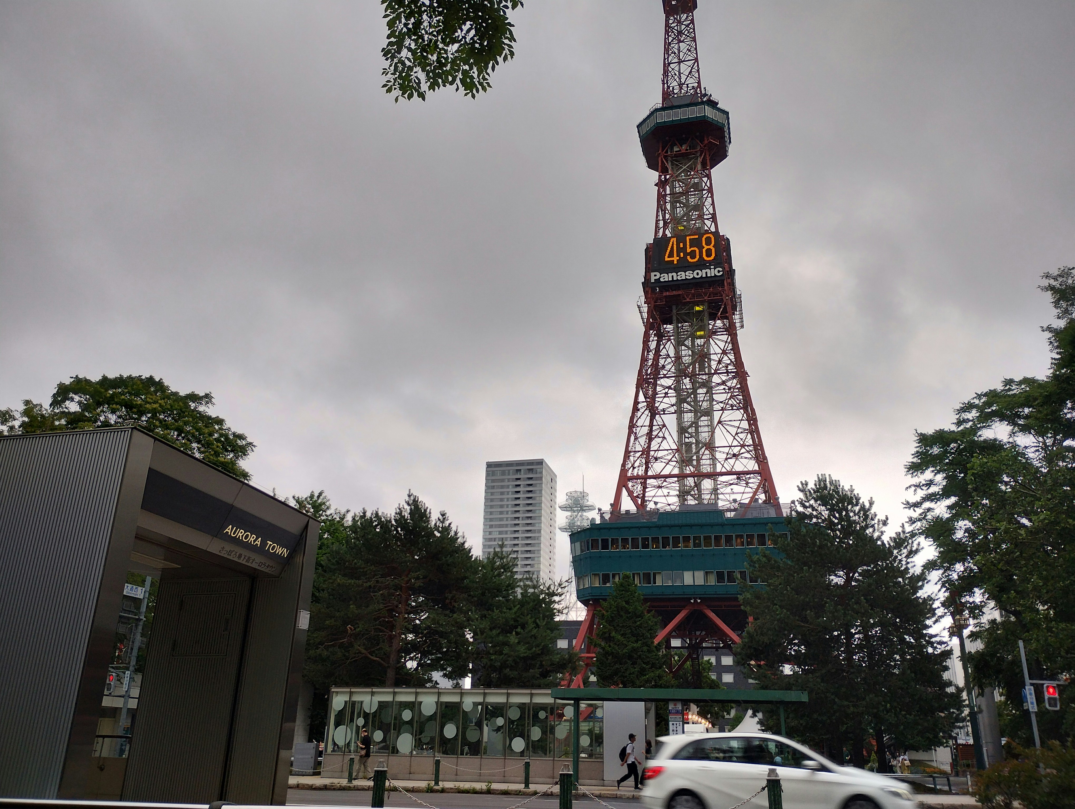 红白色广播塔与阴天的城市景观