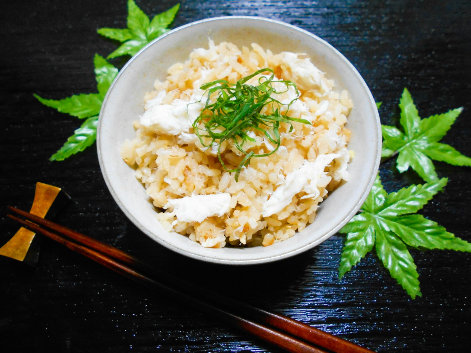深色木桌上的米飯碗上放著青蔥