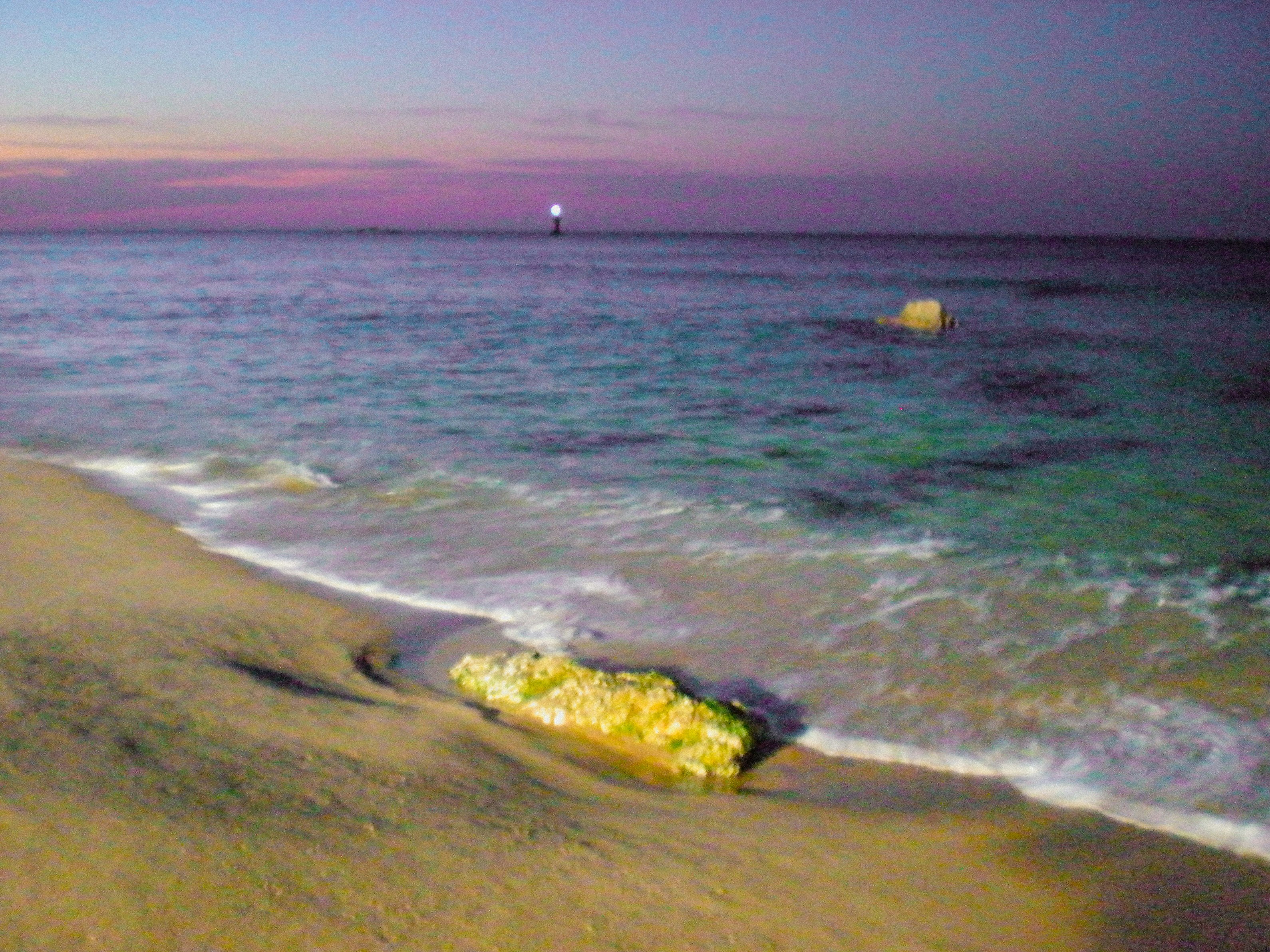 夕暮れの海辺で波が打ち寄せる砂浜の風景