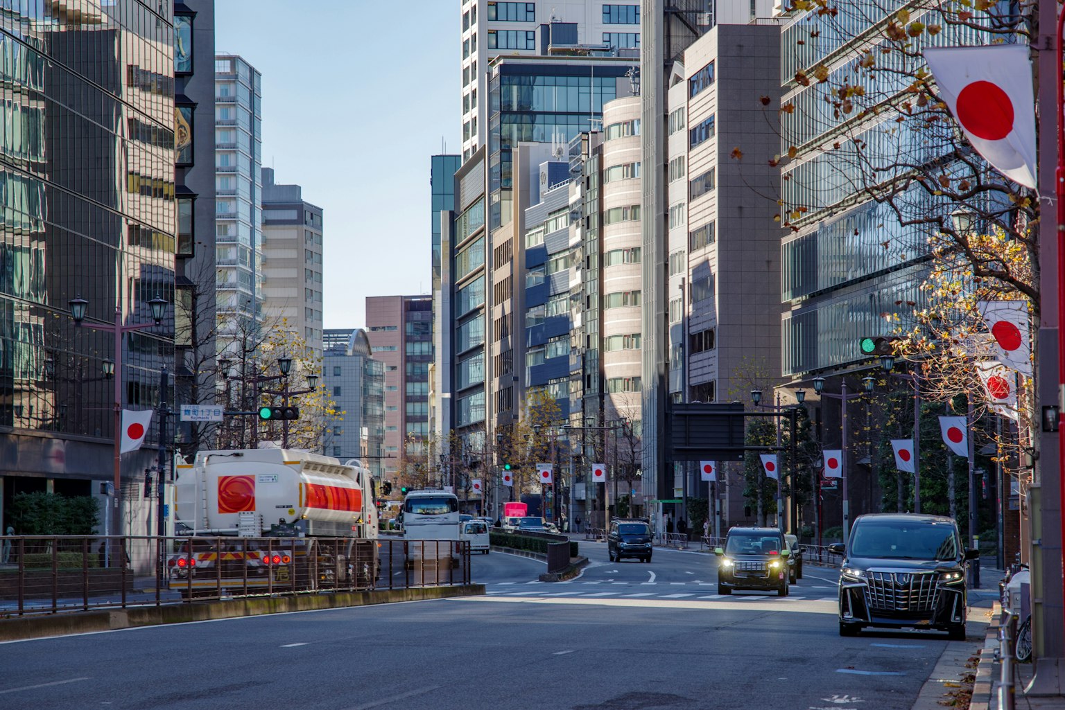 Una strada di Tokyo fiancheggiata da edifici moderni con bandiere giapponesi