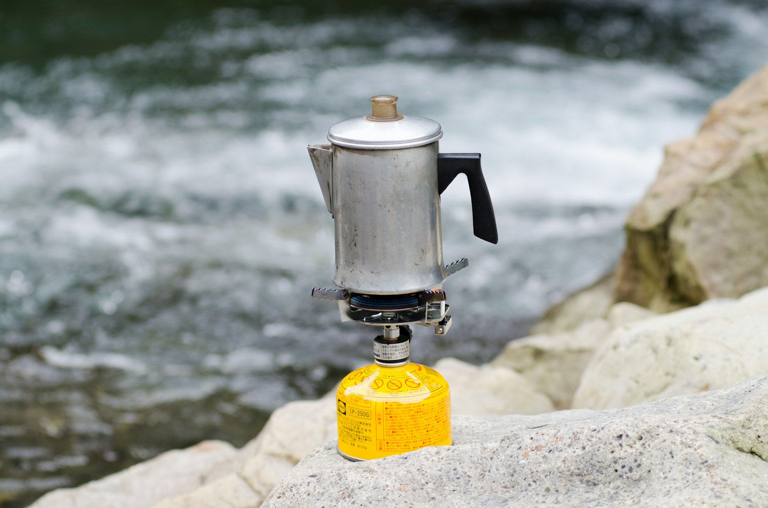 Caffettiera argentata su un serbatoio di gas giallo vicino al fiume
