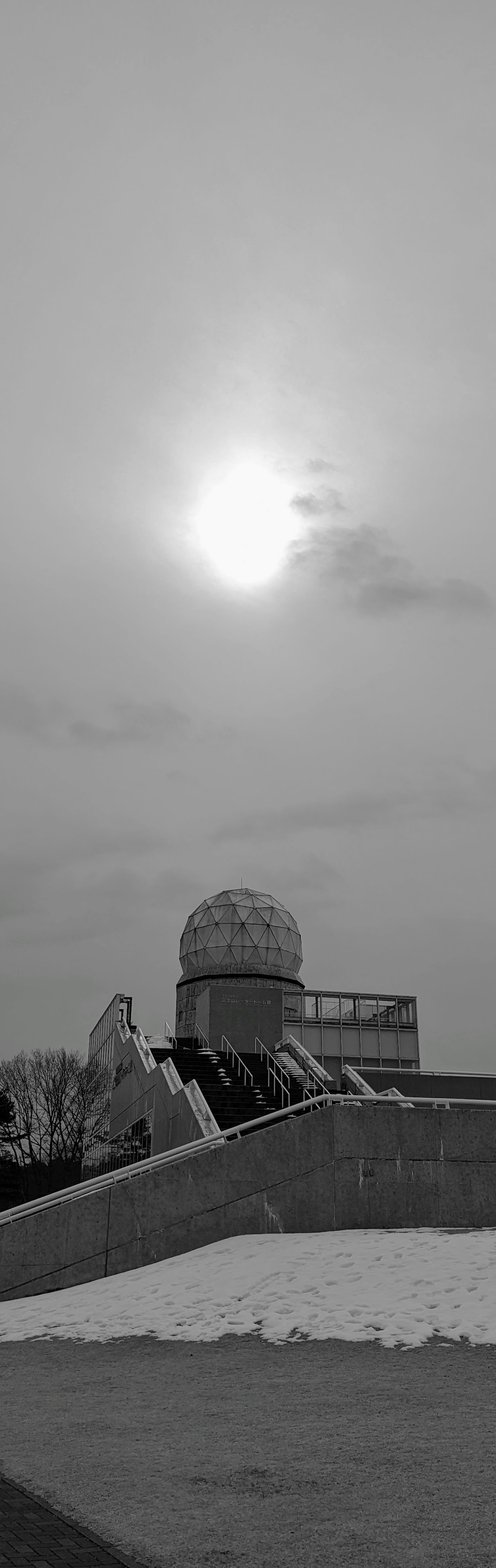 Silhouette di un edificio a forma di cupola contro un cielo in bianco e nero con il sole
