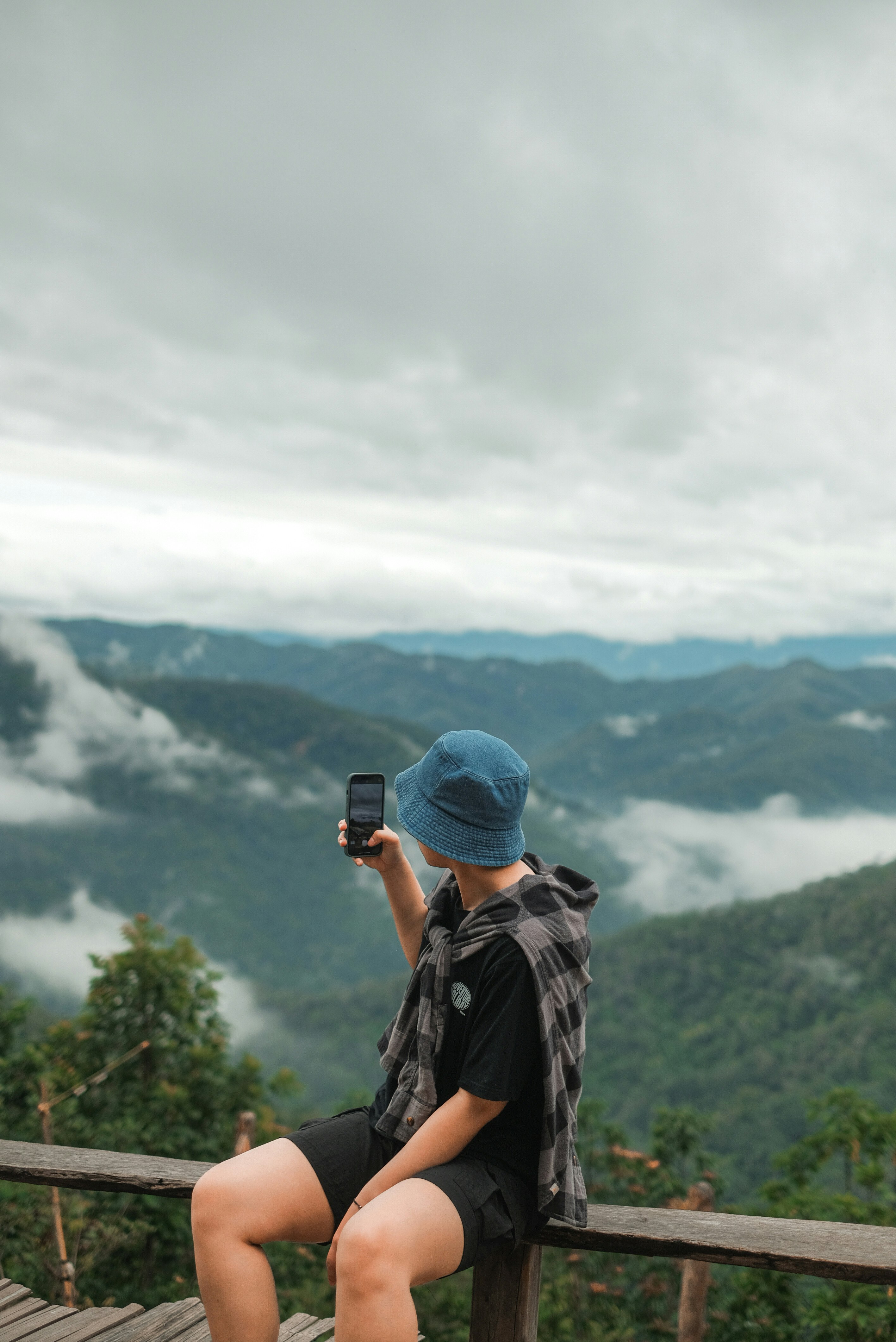 雲海の見える山の展望台でスマホを構える旅行者の後ろ姿