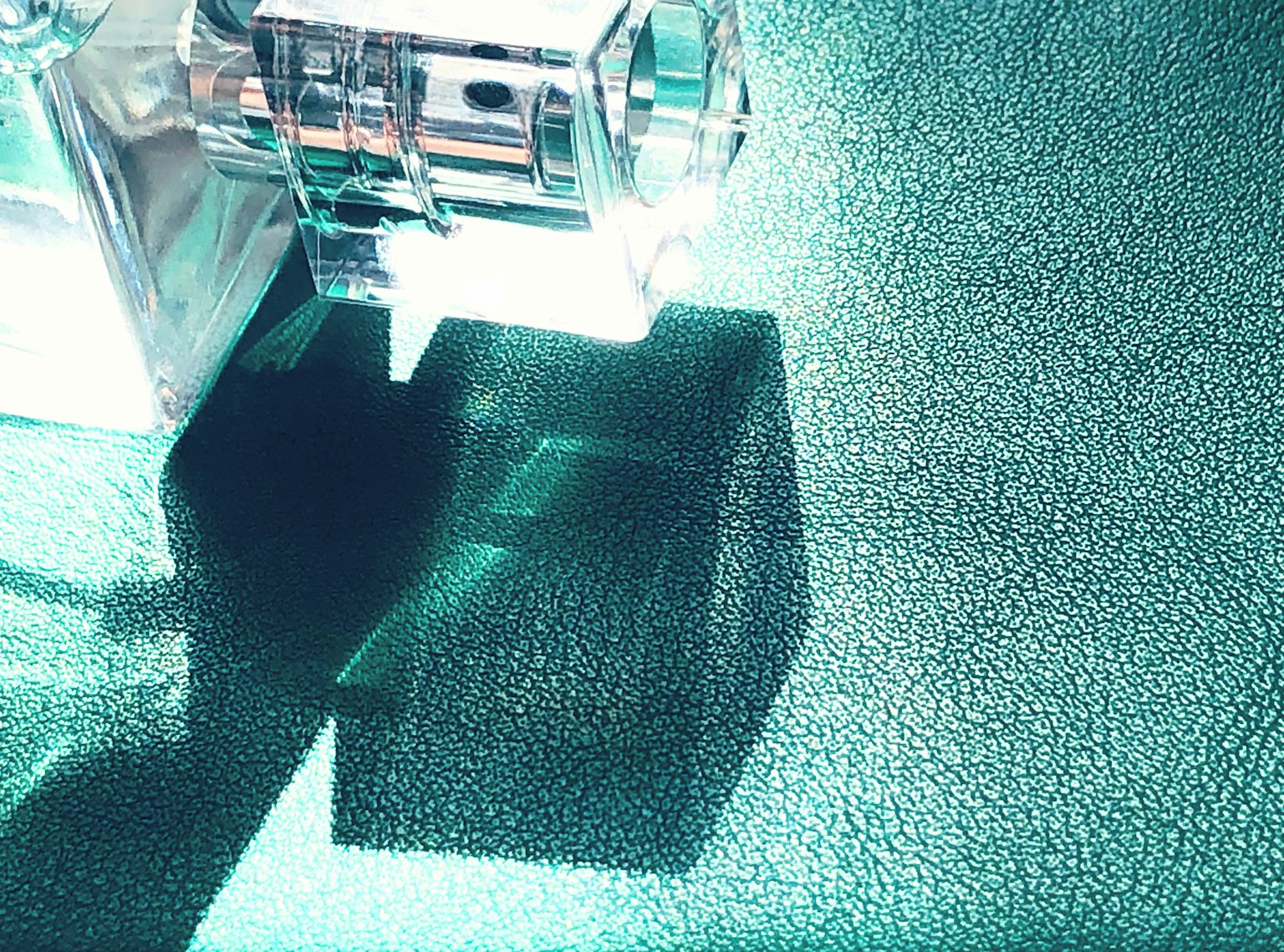 Objeto transparente proyectando una sombra sobre una superficie verde texturizada